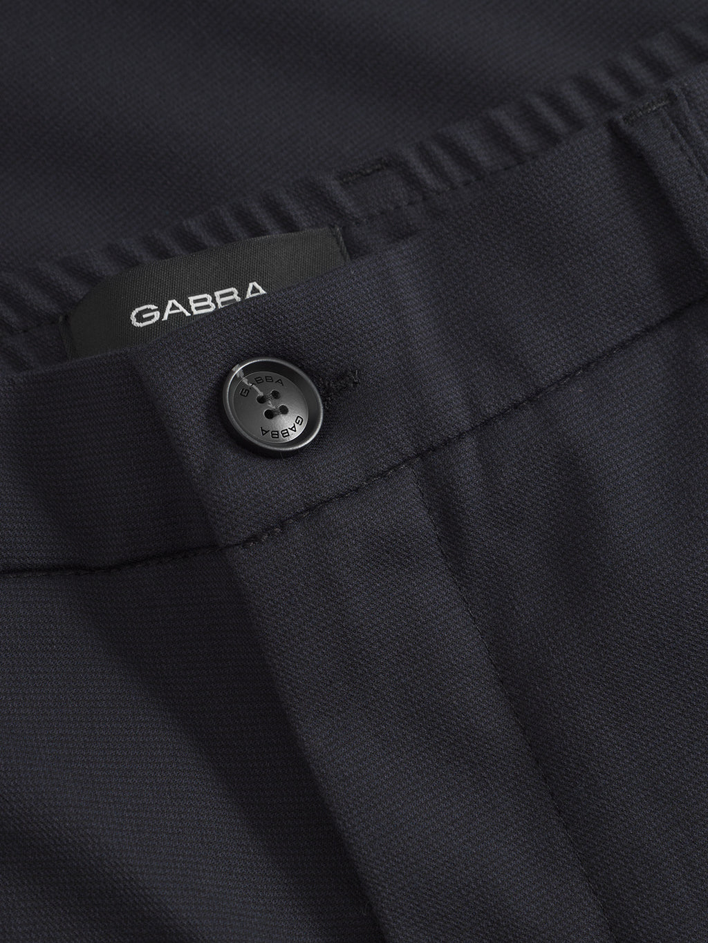 A close-up of a navy garment from Gabba showcases button fastening and a visible Napoli 19 Domo - Navy Mel. label. The textured fabric exudes classic style, promising comfort and elegance.