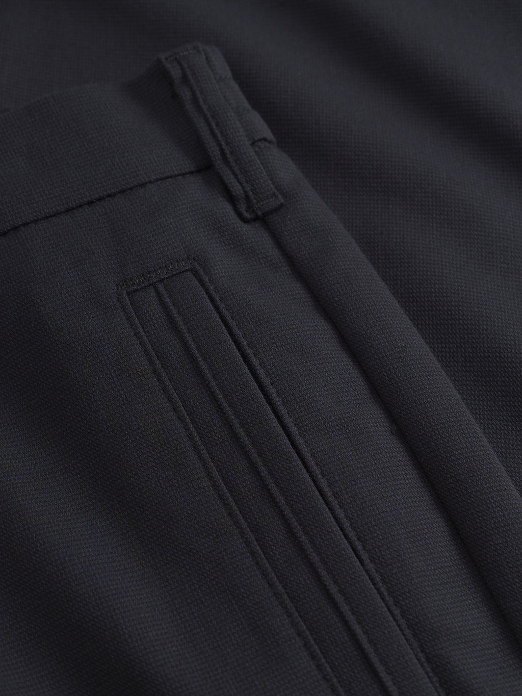 A close-up of the Napoli 19 Domo - Navy Mel. pants by Gabba features a black fabric, highlighting the side pocket with its classic style, subtle texture, and stitching detail around the pocket and waistband for both comfort and elegance.