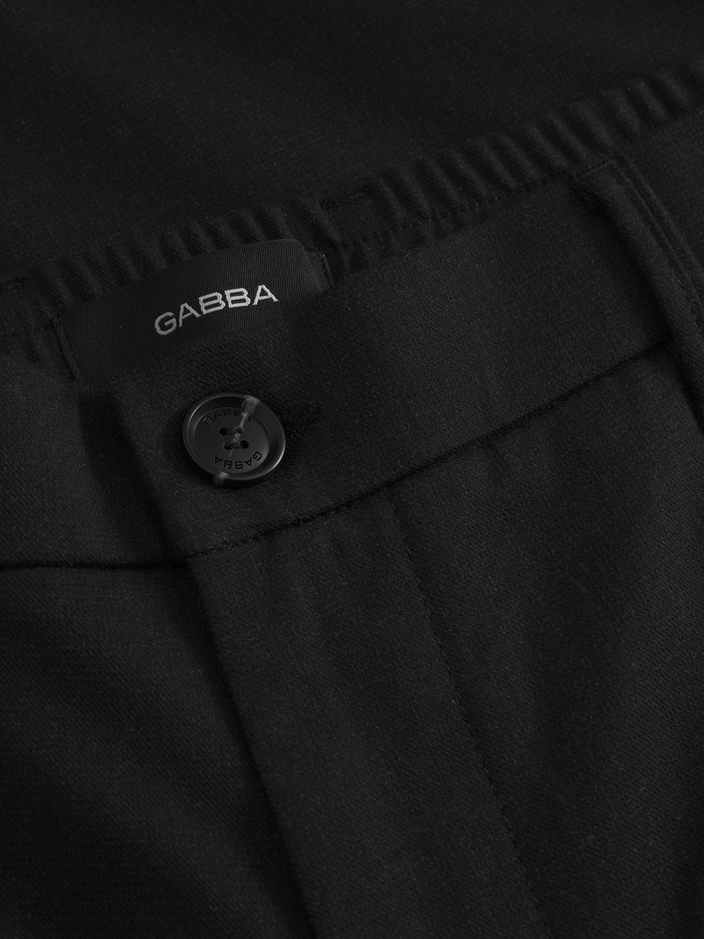 Close-up of Napoli 19 Domo - Black pants by Gabba, showcasing a visible button and a small Gabba label. The fabric is classic, smooth, and neatly stitched for comfort.