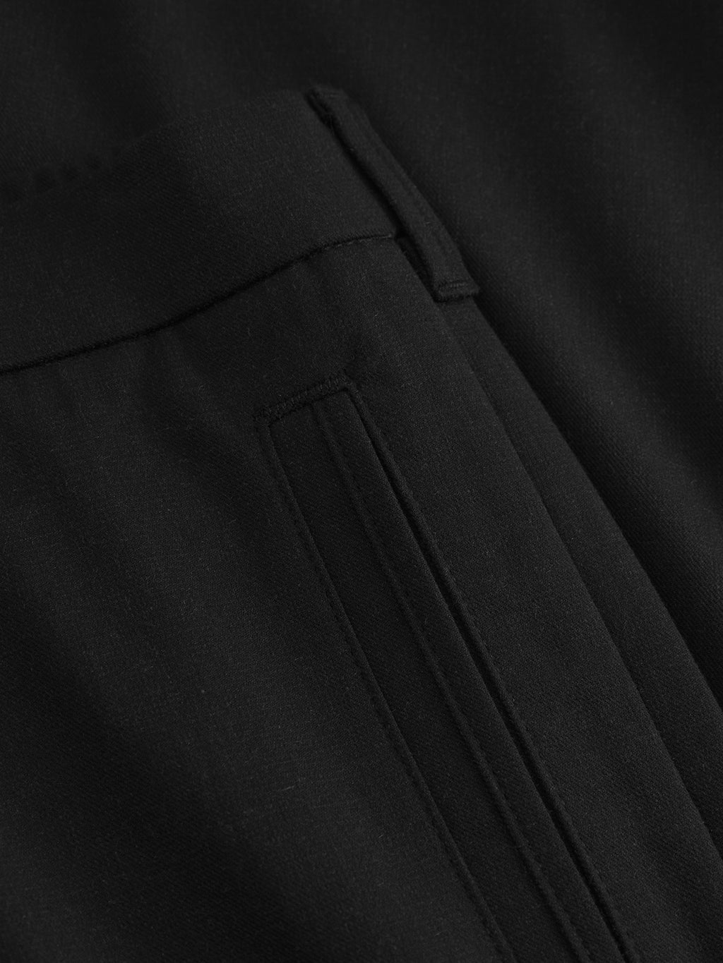 Close-up of a black fabric from the Napoli 19 Domo - Black by Gabba, highlighting a tailored seam and pocket detail. The smooth, finely woven texture suggests classic style, with the pocket neatly stitched to ensure comfort and sophistication.