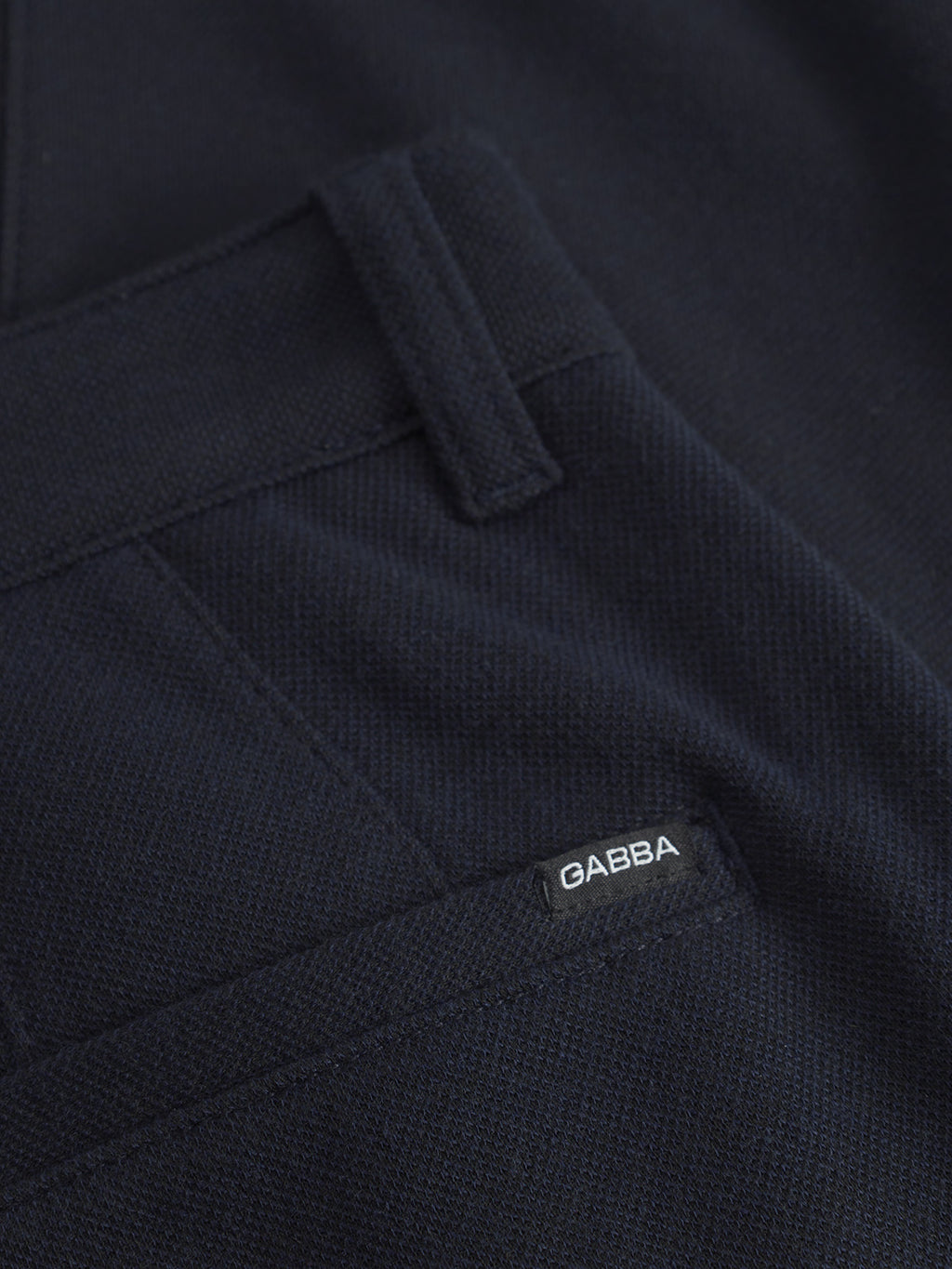 The close-up highlights Venza GKnit - Navys textured navy blue fabric from Gabba. A partially visible small white label with Gabba is sewn near a pocket, and its slightly glossy finish offers a sleek, forever-classic appearance.