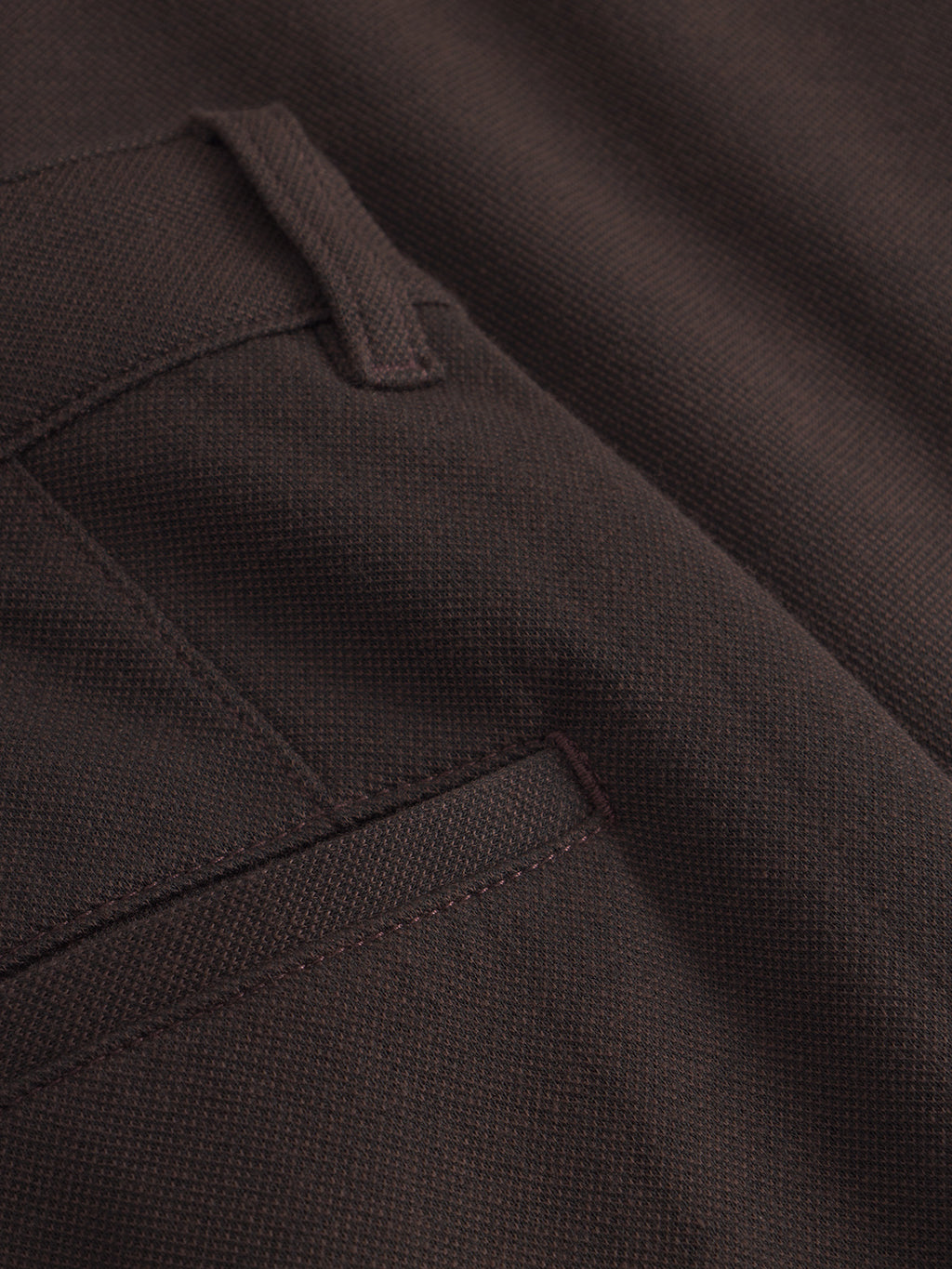 Close-up of Venza GKnit - Brown by Gabba, featuring a textured weave and innovative knitting. The image highlights a pocket and belt loop, suggesting its part of straight-fitted pants. Visible stitching enhances its structured design.