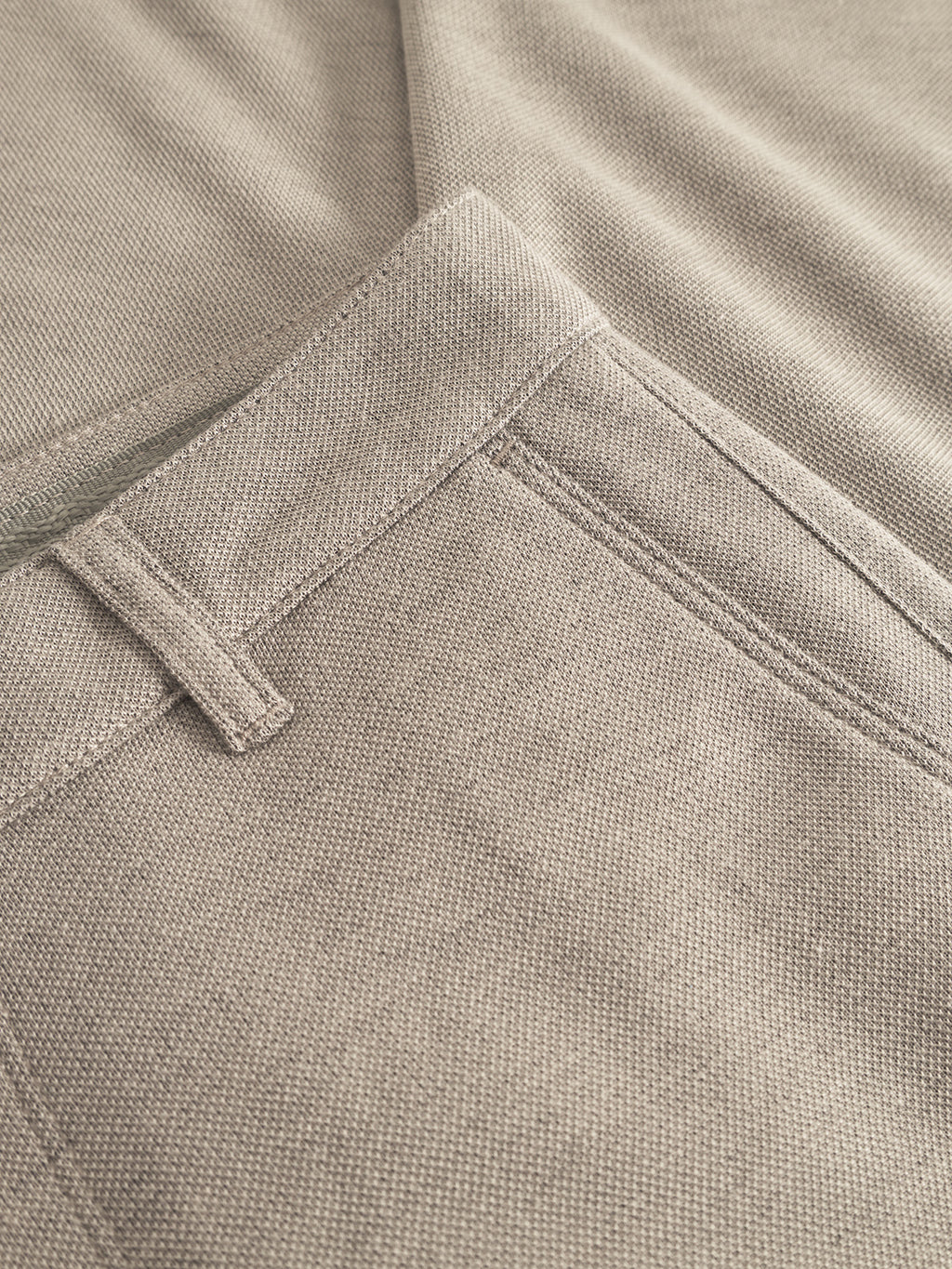 Close-up of Venza GKnit pants by Gabba in light green, highlighting the waistband and pocket. The innovative structured fabric beautifully showcases texture, weave, and natural material.