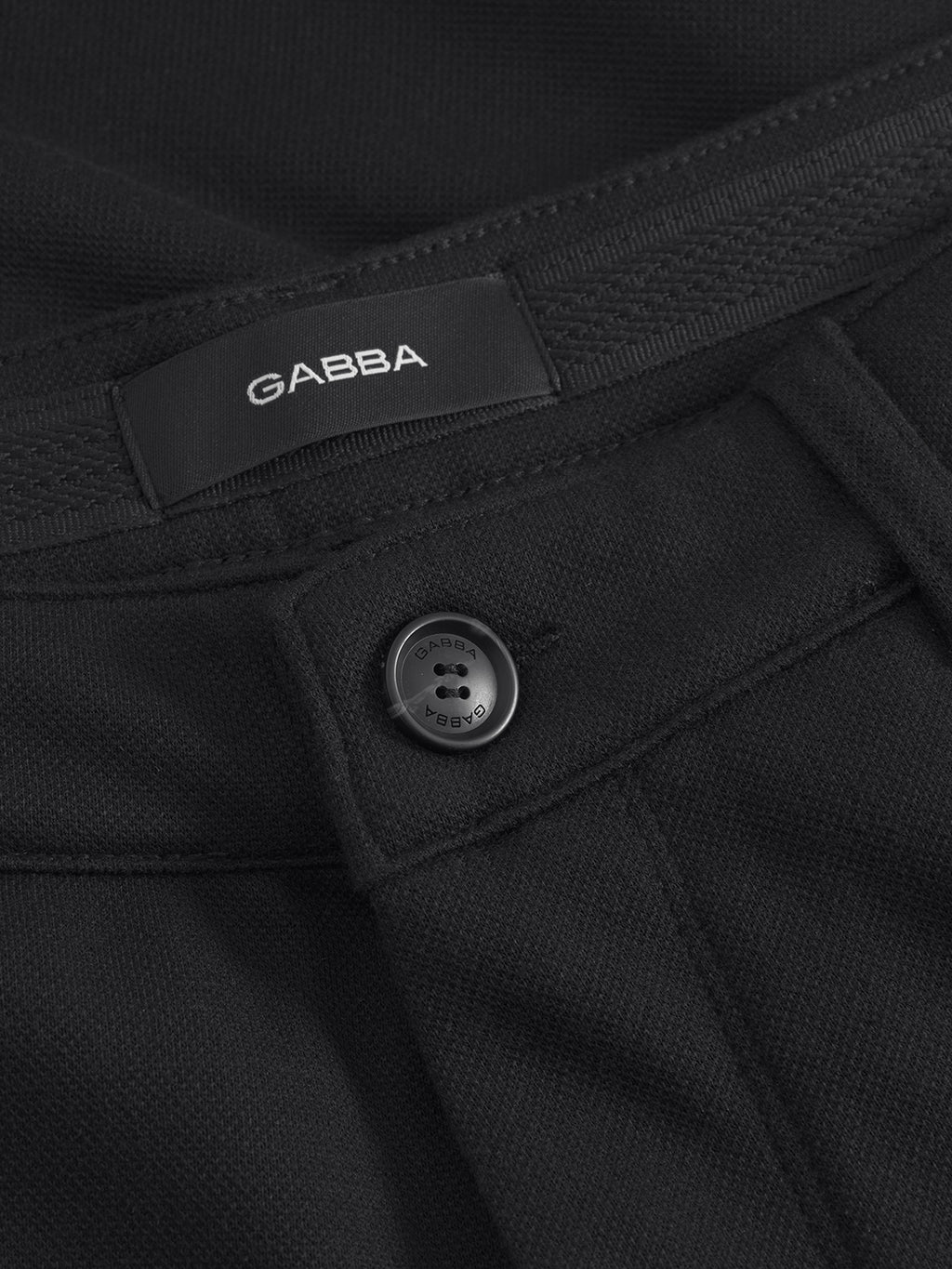 Close-up of Gabbas Venza GKnit - Meteorite pants, featuring a button and partial waistband view. The textured fabric and innovative structure enhance sophistication.
