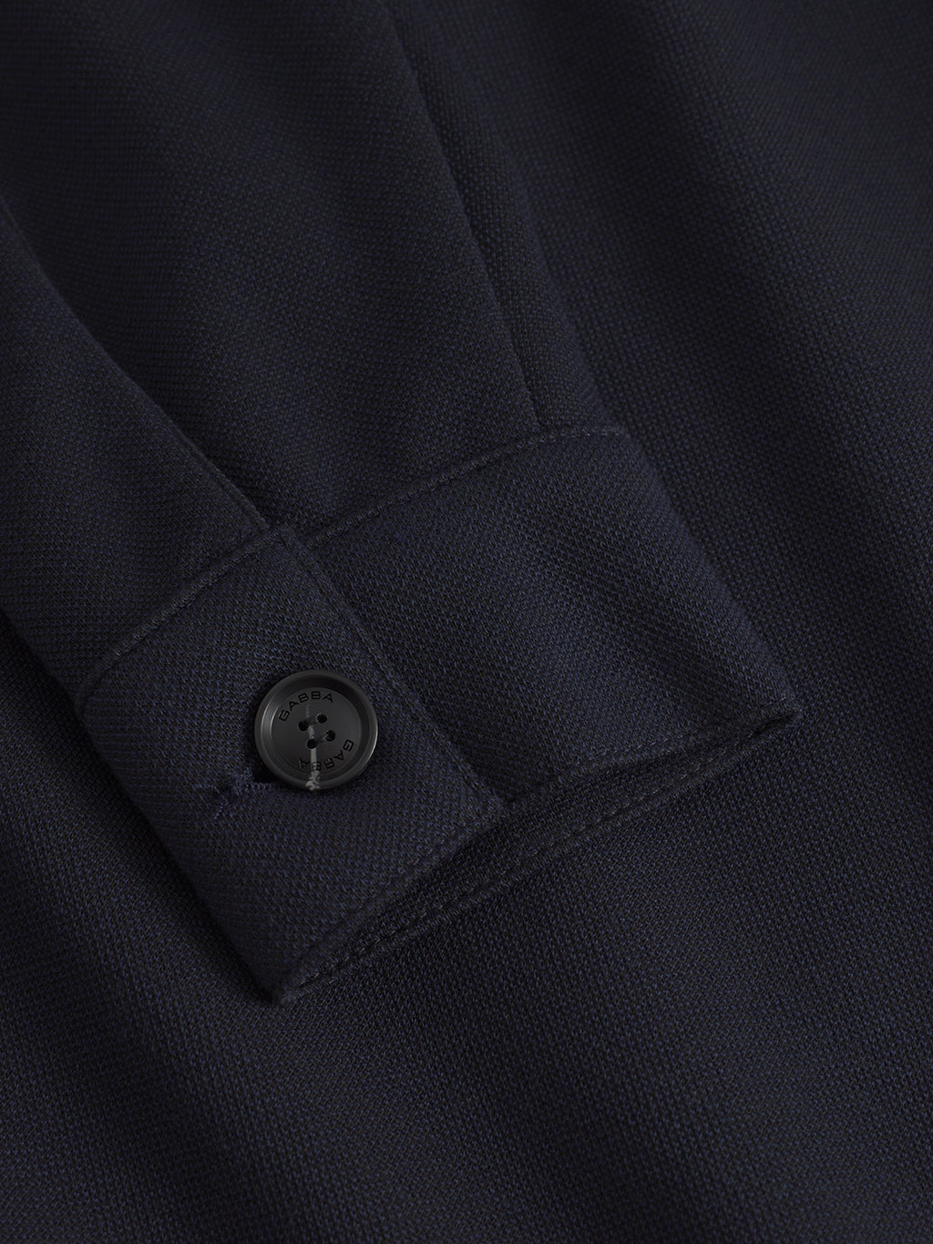 Close-up of Gabbas Toto Gknit in Navy, featuring a textured viscose mix fabric and a black button. The button, sewn with dark thread, is fastened to a folded section of the material, adding subtle charm to an everyday look.