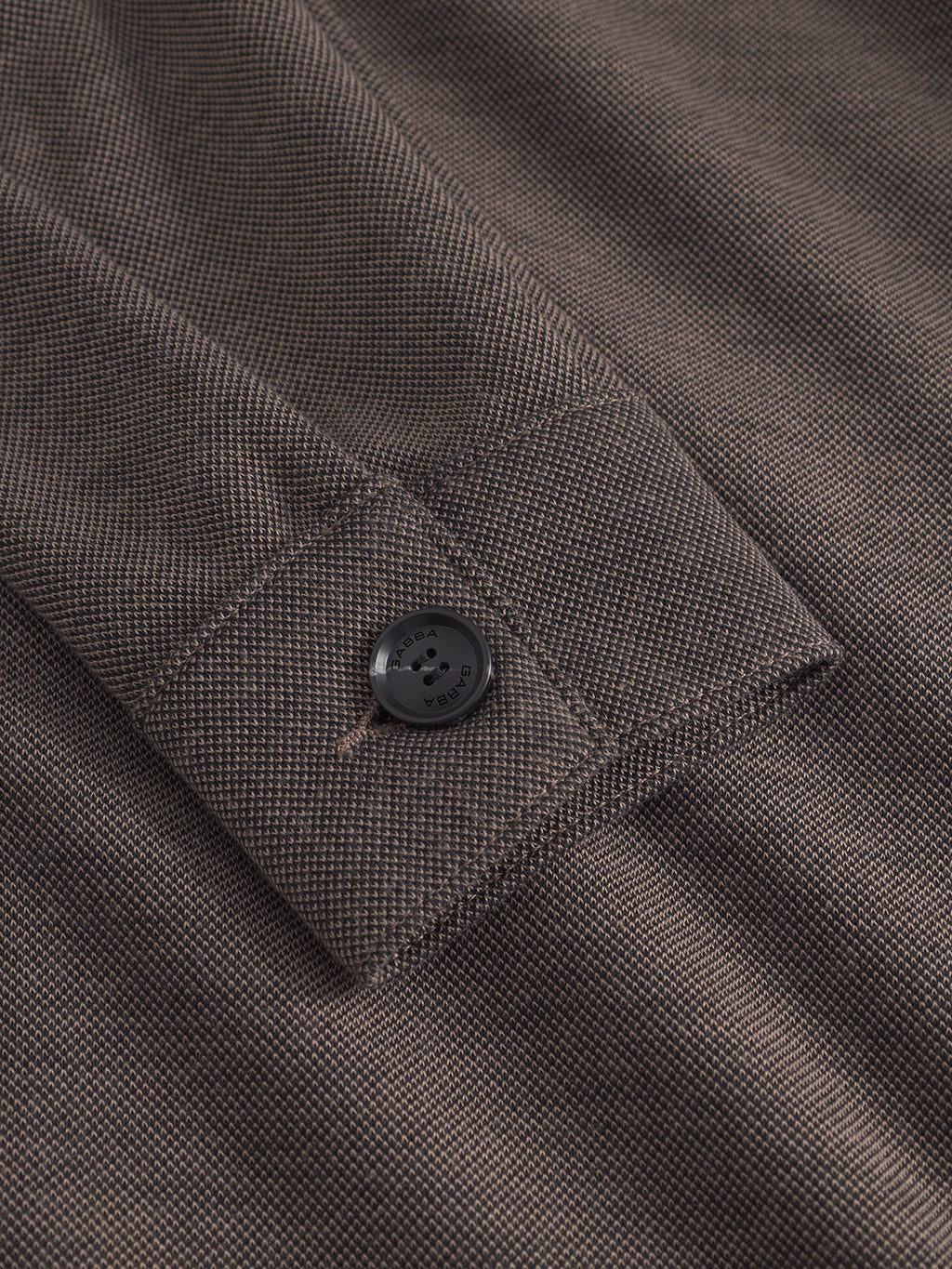 A detailed view of Toto Gknit - Sand by Gabba shows a brown viscose blend with black dots, featuring a sleeve cuff secured by an engraved black button, ideal for everyday style.