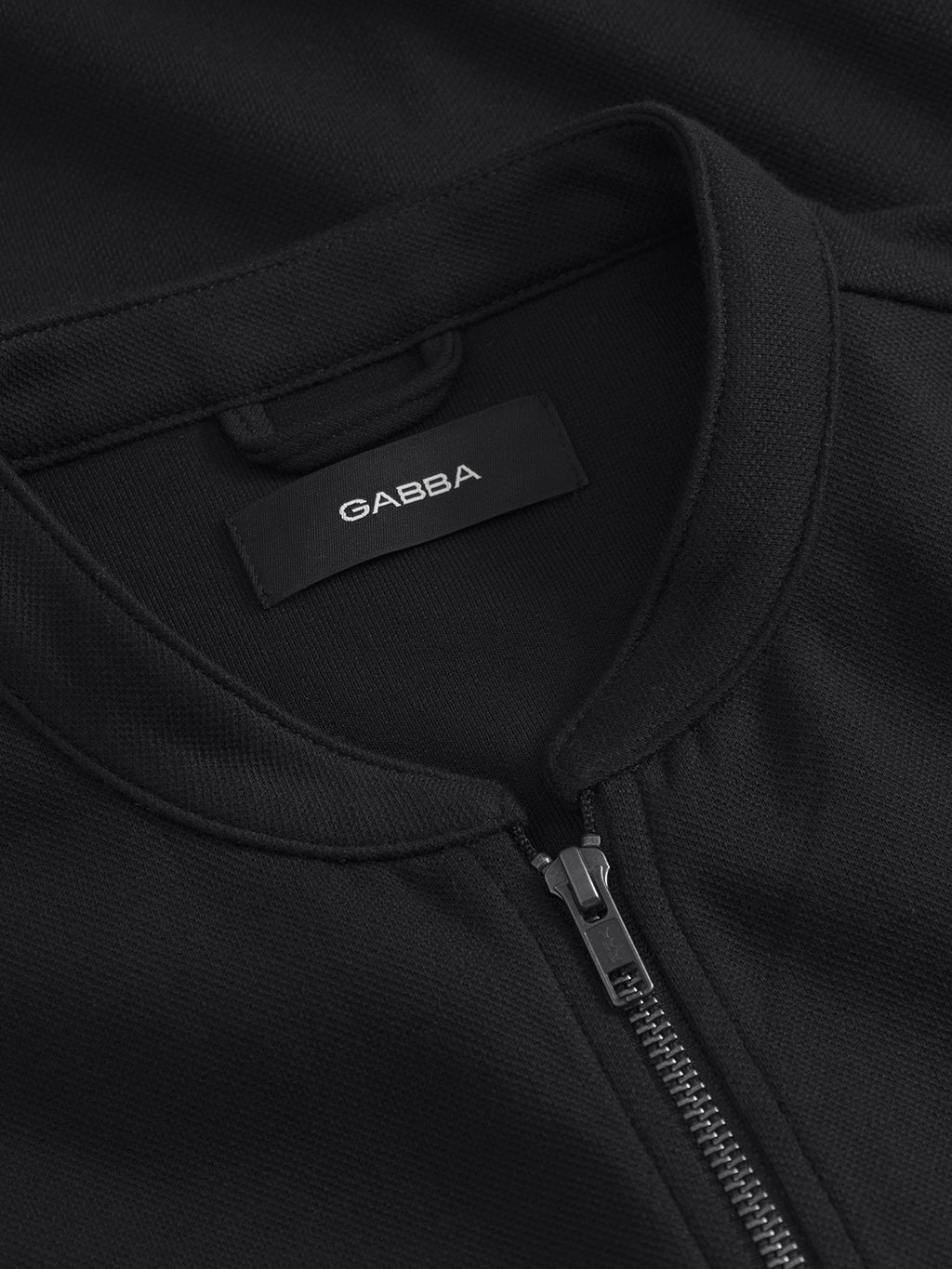 Close-up of the Toto Gknit - Meteorite by Gabba, a black zip-up jacket with a silver zipper to elevate your style. Inside is a black Gabba label. The textured fabric and detailed stitching indicate a premium viscose mix.