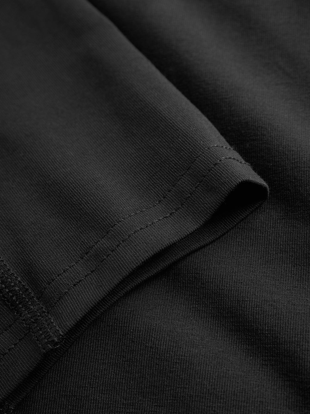 A close-up of the black fabric features visible stitching along the edge with a subtle Gabba logo. The smooth, slightly glossy texture of the Trunk New - Black is highlighted by its folded-over hem detail.