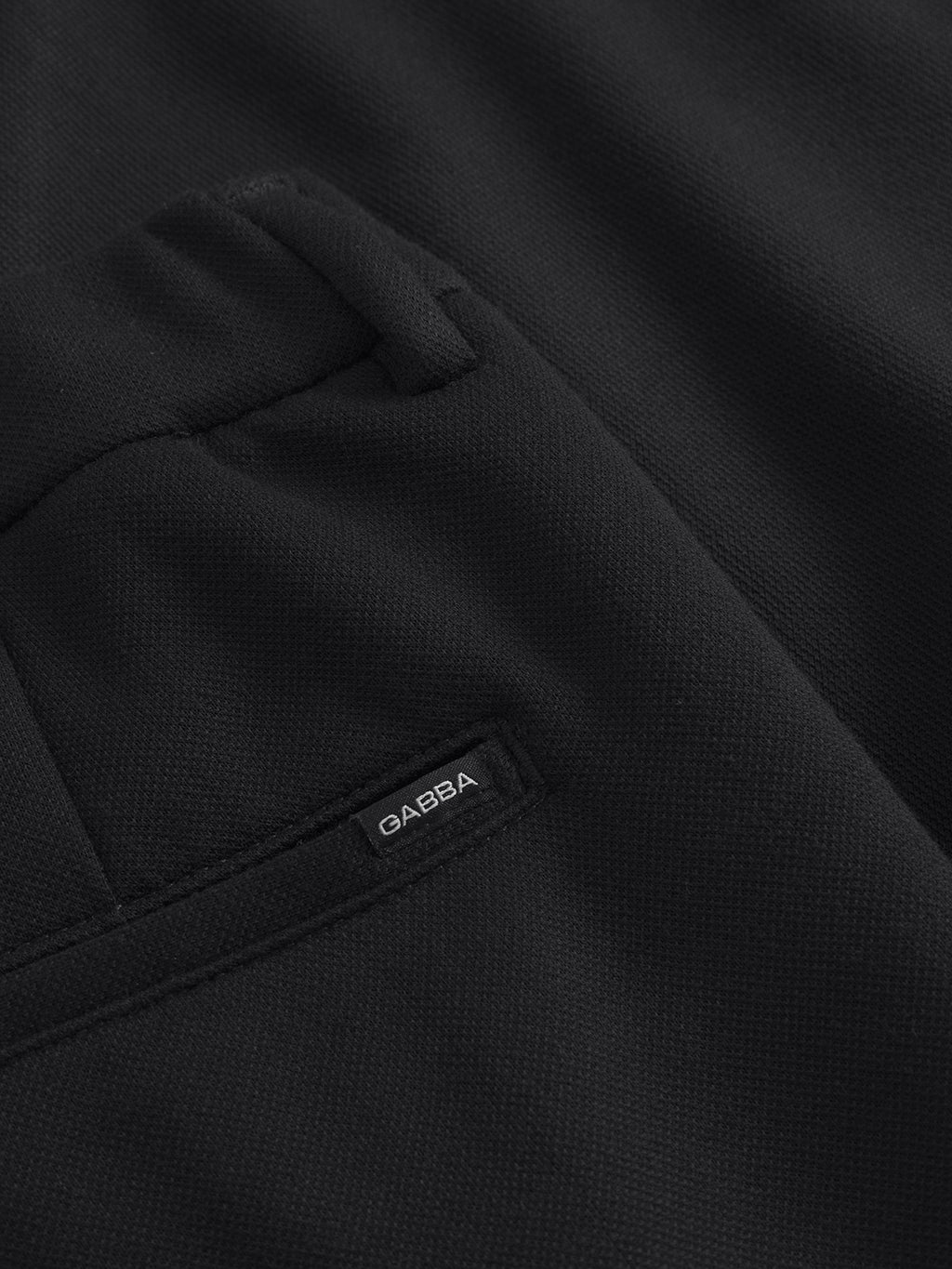 A close-up of the Tito GKnit - Meteorite fabric reveals its textured surface, pocket, and a small Gabba label. The image showcases detailed stitching and innovative knit structure, characteristic of these regular straight-fit pants.