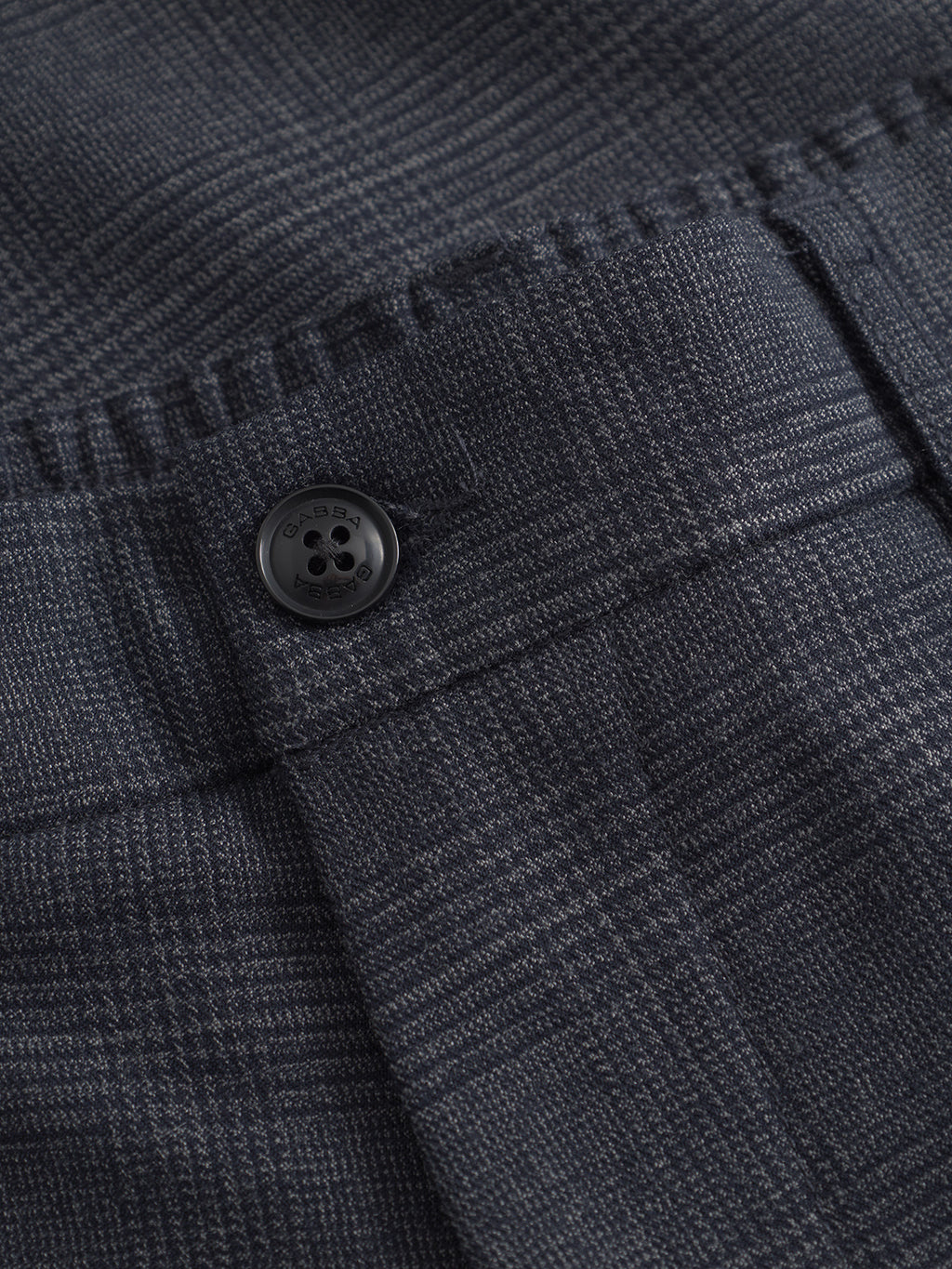 Close-up of a dark plaid fabric and black button, echoing the classic Gabba Napoli 19 Field - Navy style. It features a subtle gray checked pattern, adding texture. The button is on a flap, enhancing comfort and detailing.