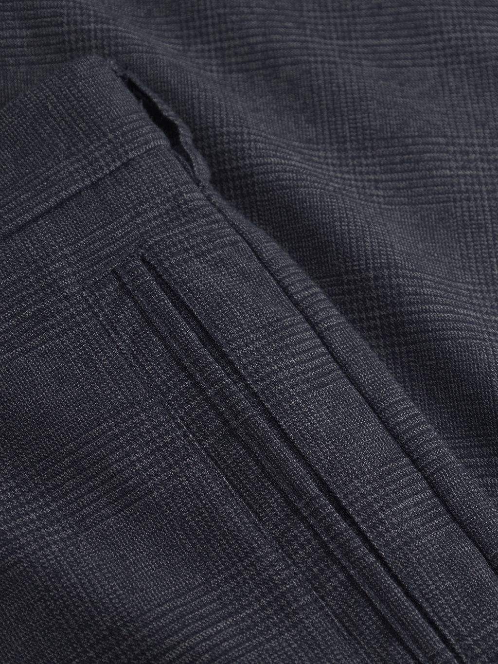 A close-up of the Napoli 19 Field - Navy by Gabba showcases a dark gray plaid fabric with a subtle checkered pattern. The image features a seam and pocket, highlighting the texture and detailed stitching for style and comfort reminiscent of classic field pants.