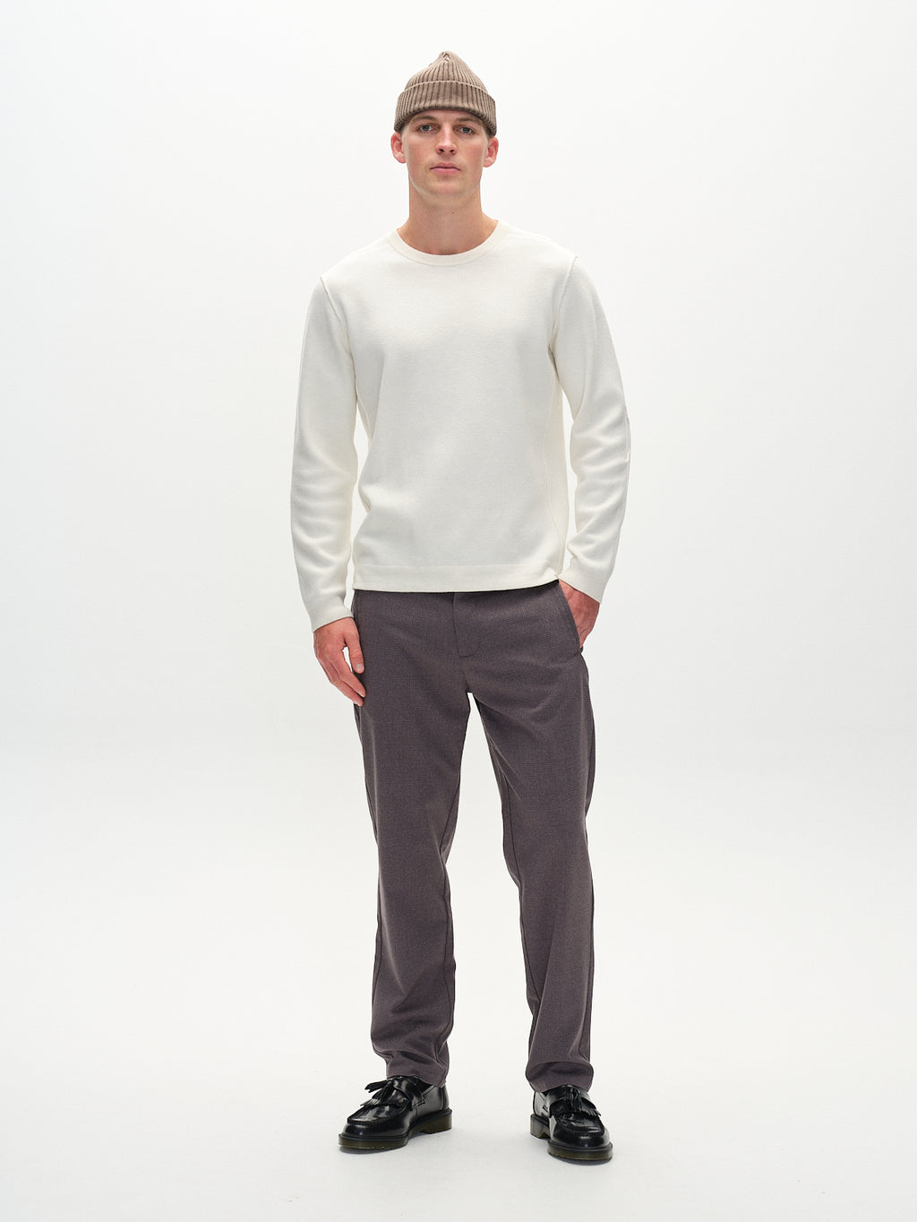 A person in a beige knit beanie and white long-sleeve shirt pairs effortlessly with Gabbas Napoli 19 Field Pants in Grey, standing against a plain white background and embodying classic style with comfort.