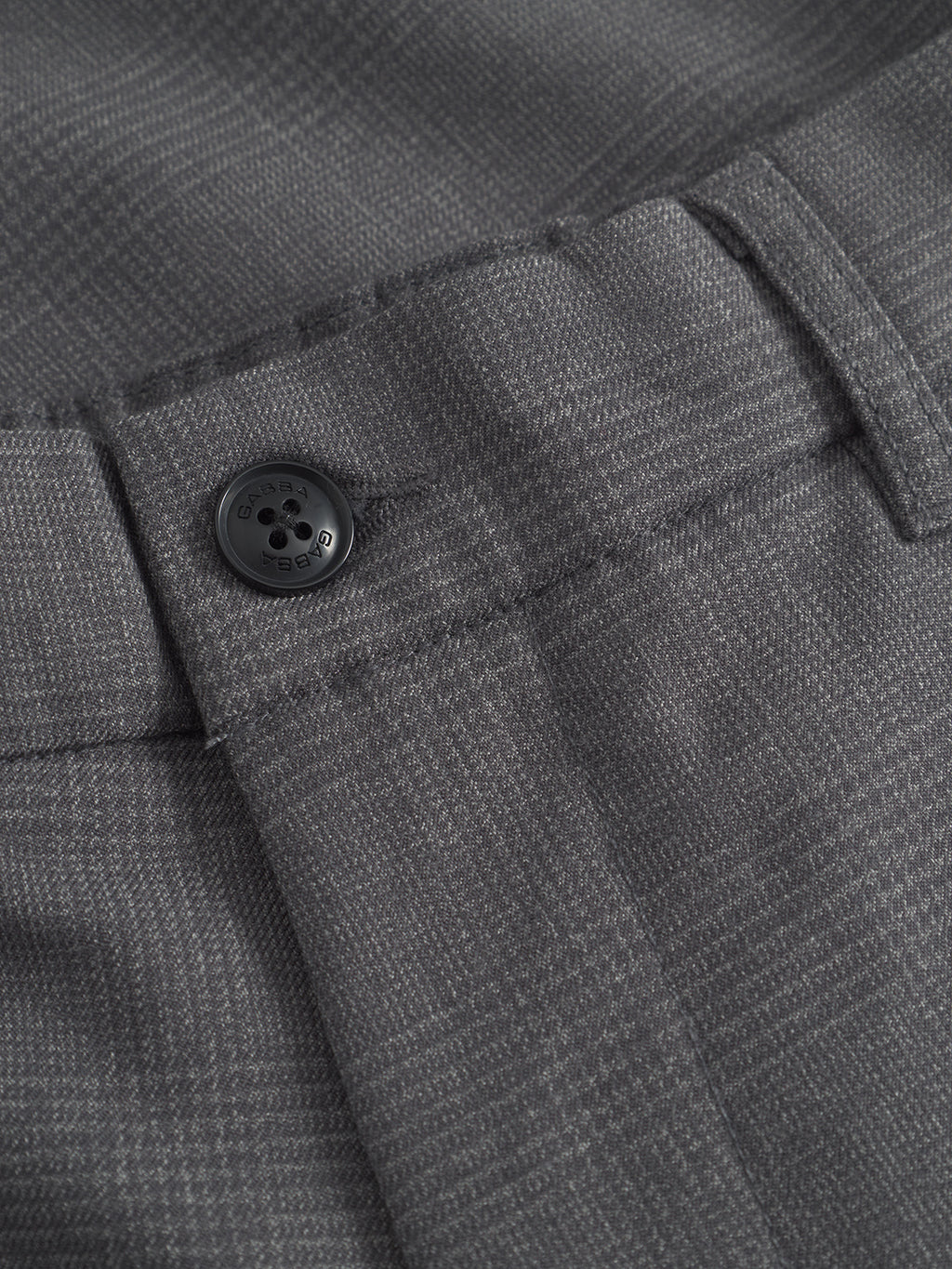 Close-up of the Napoli 19 Field - Grey pants by Gabba showcases a classic style with a subtle checkered pattern. The buttonhole with a black button is highlighted, displaying the texture and details of the comfortable fabric.