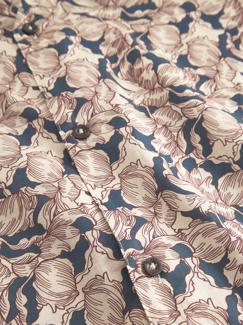 The Sven Reg Resort Epo SS by Gabba features retro floral patterns in maroon and beige with black buttons on a navy blue background, exuding vintage charm. Perfect for a premium 100% cotton shirt.