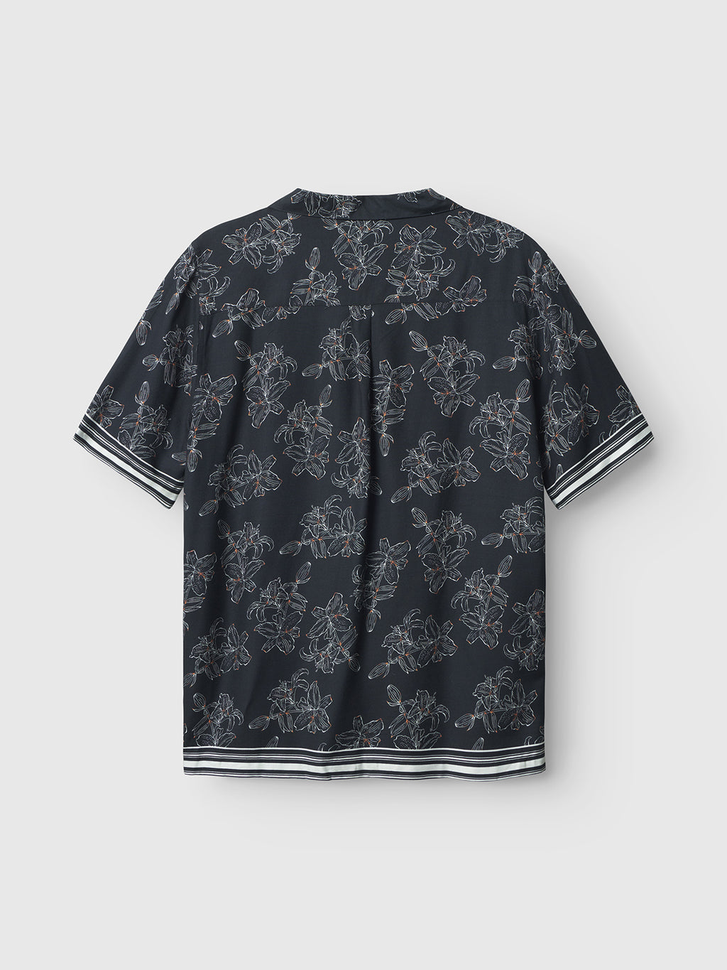 The back view of the Gabba Sven Reg Resort Lofi SS - Flower Mix shirt showcases tropical floral patterns on a dark short-sleeve design. It features striped cuffs and hem, giving off a resort-inspired vibe against a plain light gray background.