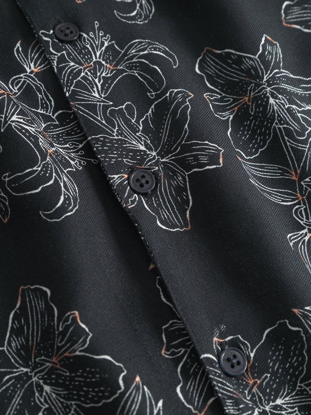 Close-up of Gabbas Sven Reg Resort Lofi SS - Flower Mix shirt, showcasing tropical floral patterns with white outlines on black fabric and adorned with black buttons, perfect for a vacation-ready vibe.