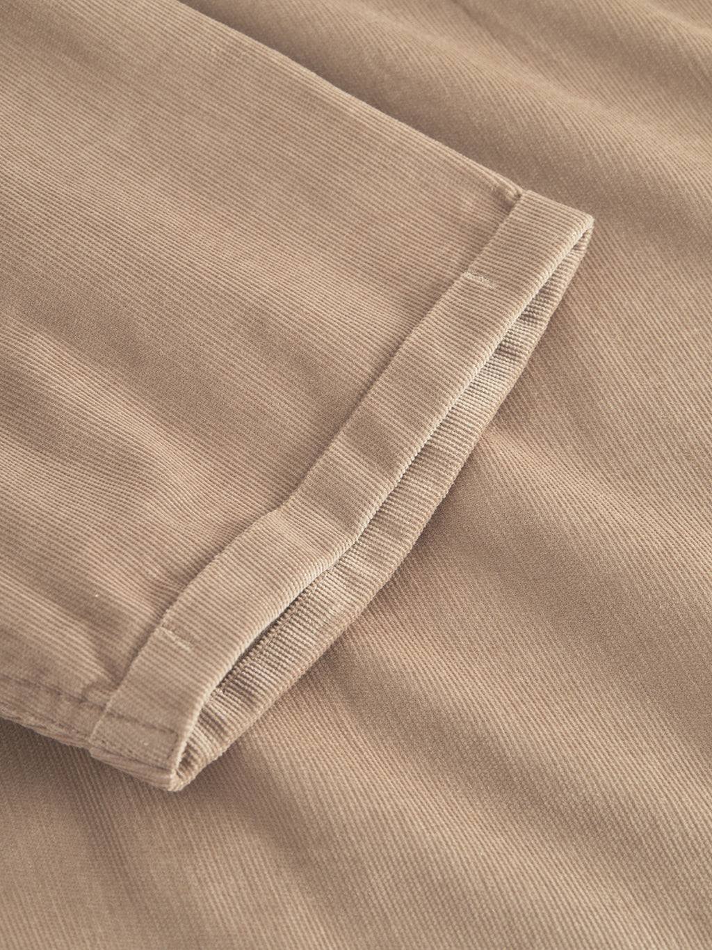 Close-up of Sven Reg Cord SS - Sand Greige by Gabba, highlighting the ribbed texture and stitching on the beige corduroy cuff. The soft, 100% cotton material is slightly folded, showcasing its subtle sheen and intricate details typical of a premium shirt.