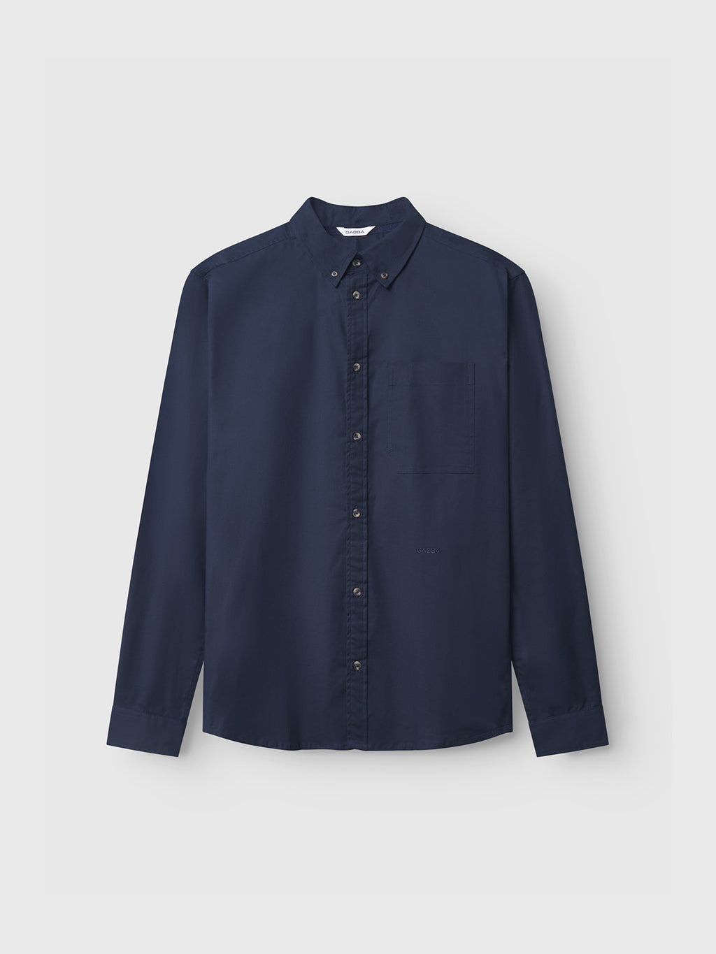 Laid flat on a light gray background, the Bent Reg Ox LS by Gabba in Dark Navy is a long-sleeve button-up shirt featuring a classic collar and pocket on the left chest. Its timeless design promises all-day comfort and elegant simplicity.