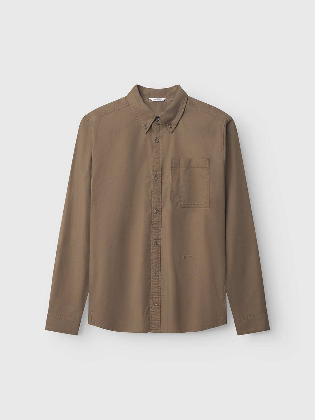 The Gabba Bent Reg Ox LS shirt in brown is a versatile cotton button-up with a collar, long sleeves, and a single chest pocket, suitable for both formal and casual wear. It is showcased on a plain light gray background.