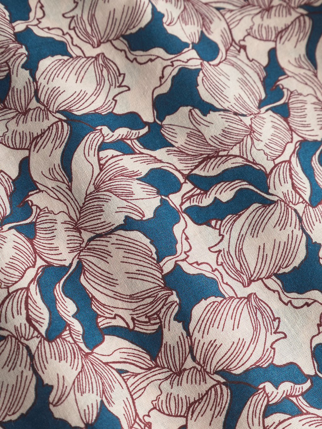 A close-up of the Bandana Epo fabric by Gabba reveals an elegant blue pattern with red outlined retro flowers, reminiscent of a classic bandanas intricate design.