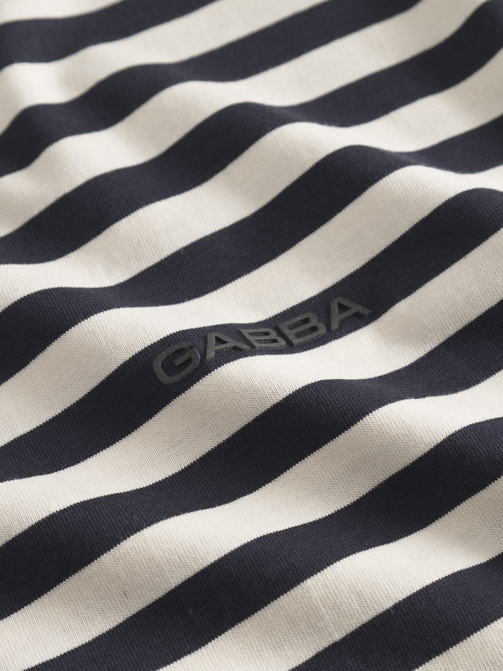 Close-up of the Dune Logo Stripes SS GOTS by Gabba, featuring black and white stripes on 100% organic cotton. GABBA is embroidered in black on its soft, slightly wavy surface—ideal for a basic t-shirt.