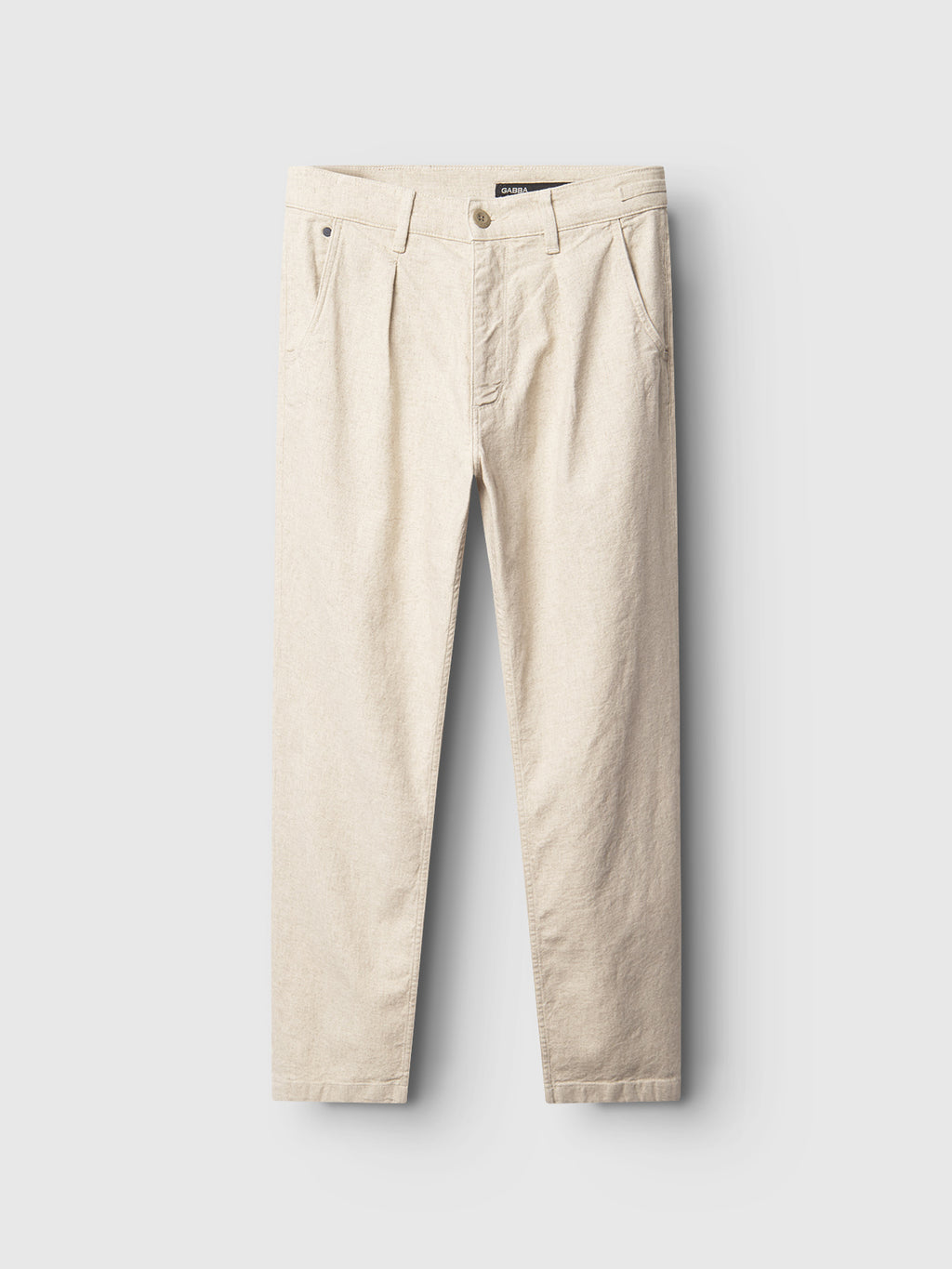 The Kyoto Hemp - Sand by Gabba are khaki pants in a relaxed tapered fit, with front pleats. They feature a button and zipper closure, side pockets, and belt loops, all neatly displayed against a light gray background.
