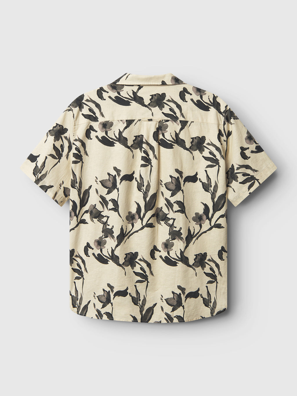 Back view of the Gabba Sven Reg Resort Bloom SS - Meteorite, a premium, relaxed fit short-sleeved shirt with a beige background and black and gray floral pattern, featuring a collar and showcasing exceptional linen quality.