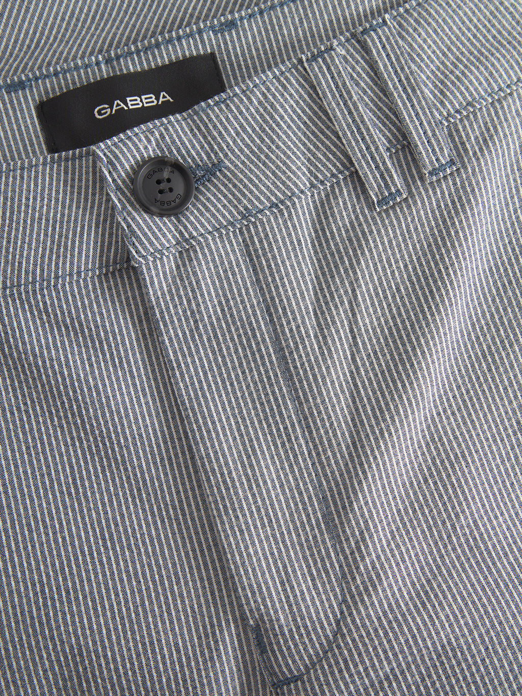 Close-up of the Jet Com2 Shorts - Navy by Gabba, showcasing a button on the waistband. These premium shorts feature thin white and light blue vertical stripes for a classic and simple design, known for their superior comfort.