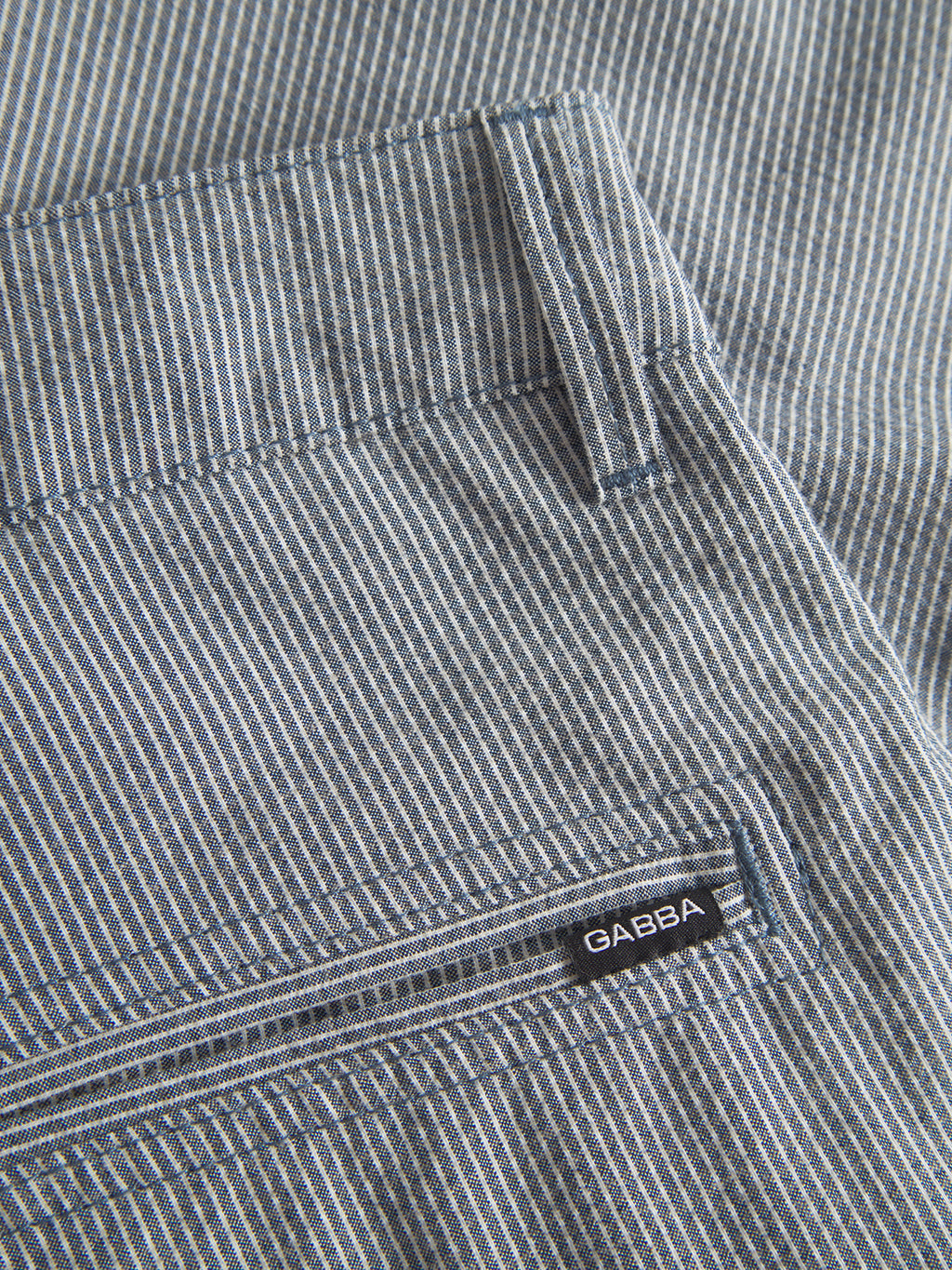 Close-up of a garments blue and white pinstriped fabric with a visible pocket and a black Gabba label. The Jet Com2 Shorts - Navy offer superior comfort, perfectly blending style and unparalleled quality for everyday wear.