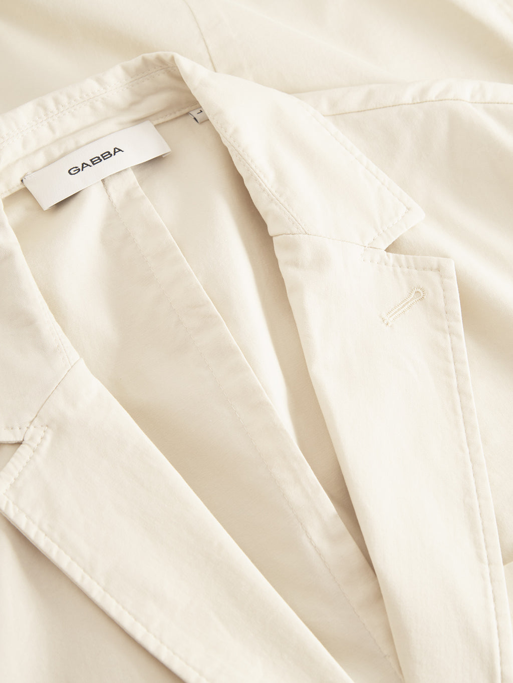 Close-up of the Josh Unite - Beige blazer by Gabba in light beige, showcasing its visible collar and lapel. Crafted from cotton stretch fabric, it offers a smooth, slightly glossy finish for a polished texture and regular fit.