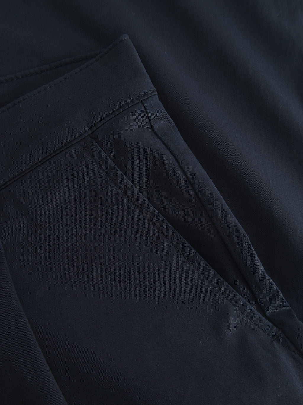 A close-up showcases the smooth navy blue fabric of the Joe Unite - Navy pants by Gabba, highlighting the side pocket with clean stitching and subtle shadows that enhance its texture and add depth to the garments casual appearance.