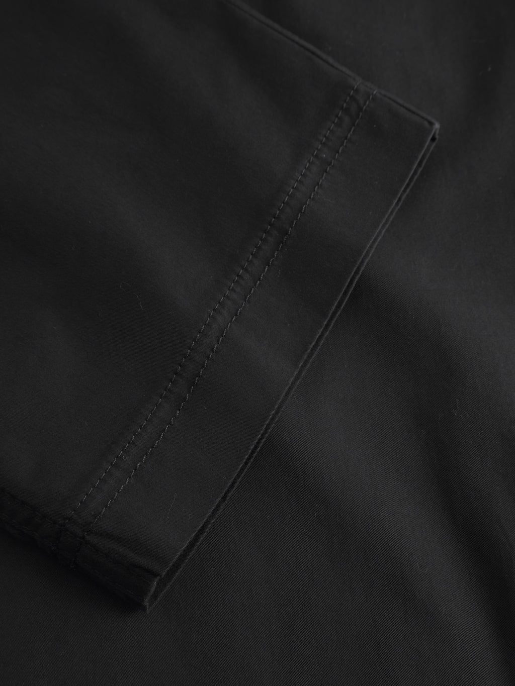 A close-up reveals the detailed stitching on the smooth, tightly woven fabric of Gabbas Joe Unite - Black. Ideal for crafting garments like relaxed-fit pants or home textiles, it promises comfort and a casual look.