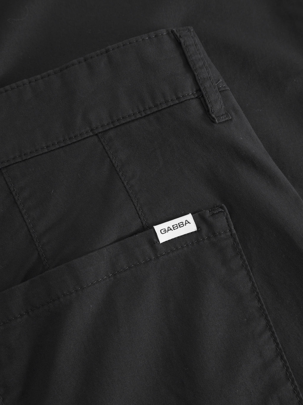 Close-up of the Joe Unite - Black fabric items shows visible seams and a small white Gabba label, presenting a casual look with relaxed fit pants and tapered legs.