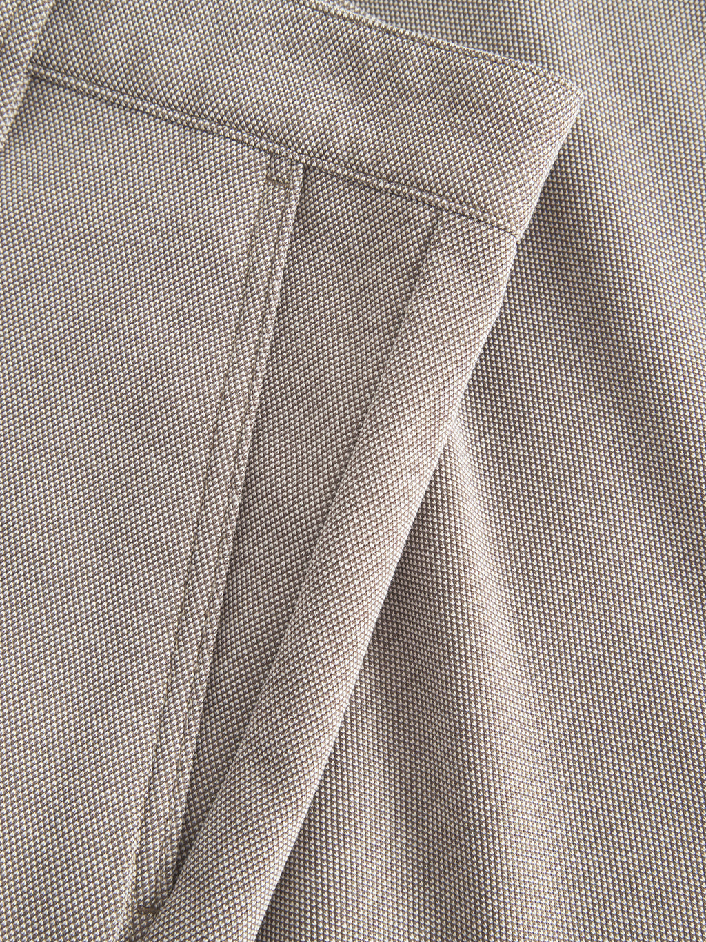Close-up of Gabbas Jet Tink - Khaki shows beige textured fabric with detailed stitching and a folded seam, common in garments or upholstery. Its durable, coarse weave enhances tactile appeal and ensures superior comfort when used in premium shorts.
