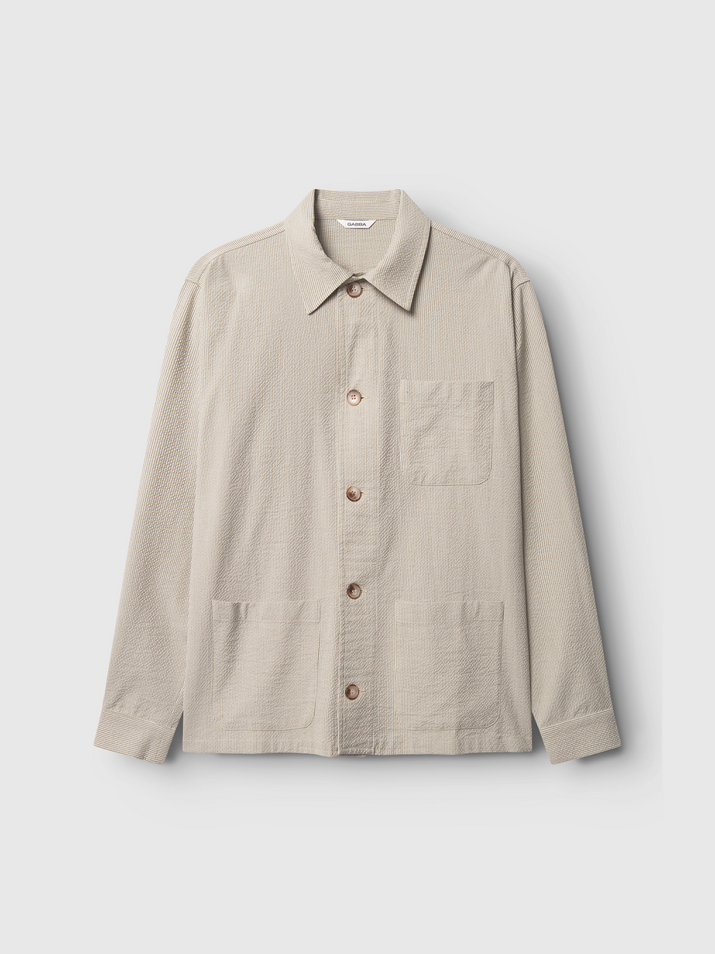 The Gabba Today Com2 – Khaki is a light beige long-sleeve button-up shirt jacket made from textured seersucker, with a collar, one chest pocket, and two front pockets, shown laid flat for a smart yet casual style.