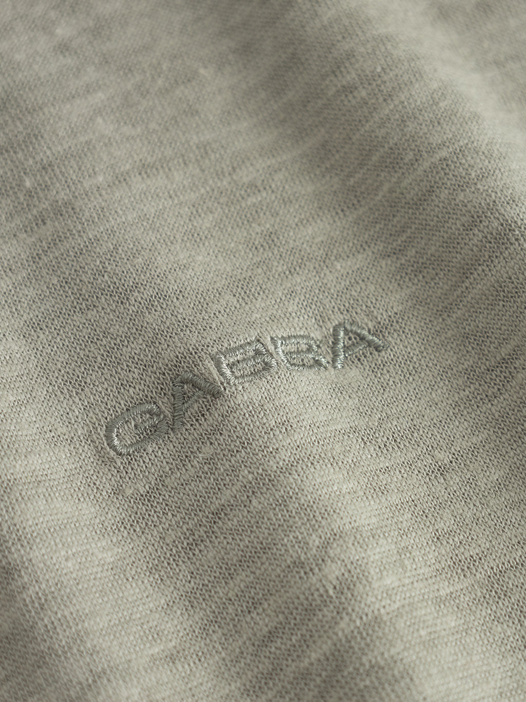 A close-up of Gabbas Duke Linen Logo SS in light green shows GABBA finely embroidered on the soft, textured fabric. The slightly heathered material features tone-on-tone stitching akin to fine linen t-shirt craftsmanship.
