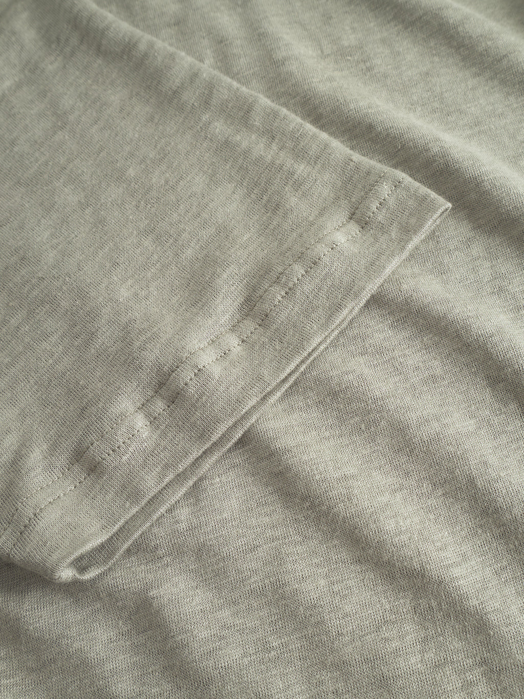 Close-up of the hem on the sleeve of Gabbas Duke Linen Logo SS in light green, showcasing tone-on-tone stitching. The detailed fabric texture and craftsmanship are visible.