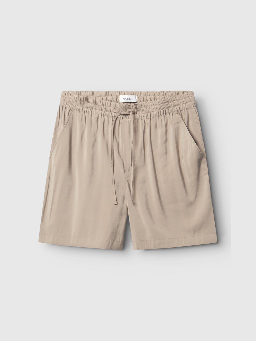 Gabba Bo Yari - Sand Greige shorts feature an elastic waistband, drawstring, side pockets, and a relaxed fit. Crafted from lightweight fabric for comfort, they are shown laid flat on a plain light background.