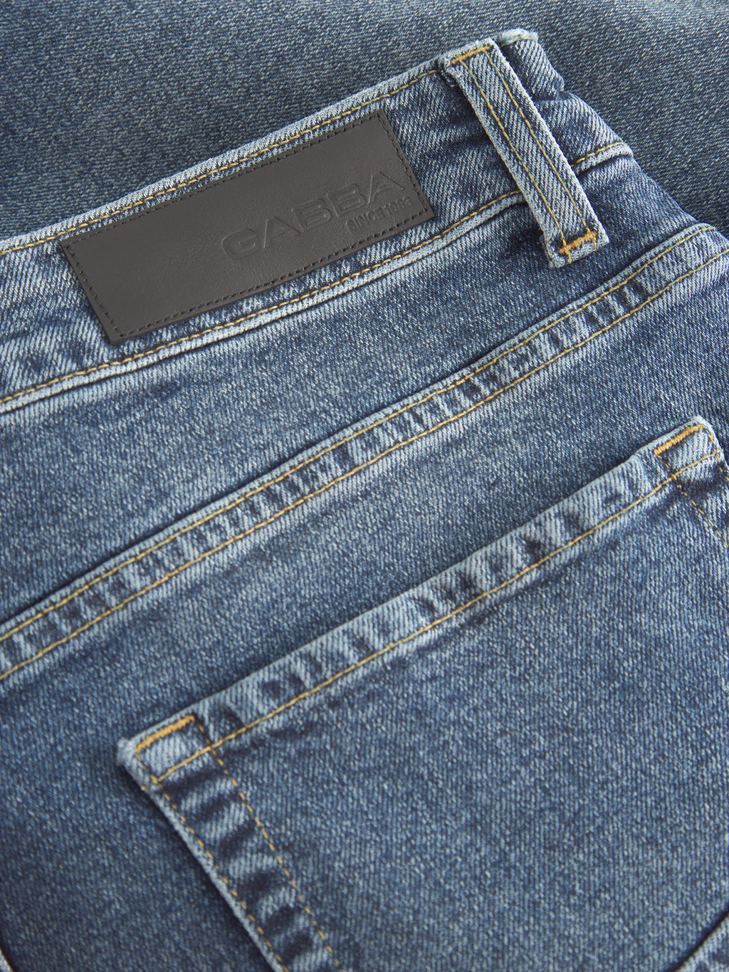Close-up of the back pocket and waistband on the Markus 5poc Dark Blue Denim jeans by Gabba, featuring visible stitching and a black leather patch with embossed text. These jeans showcase a comfortable fit that suggests recycled viscose artistry.