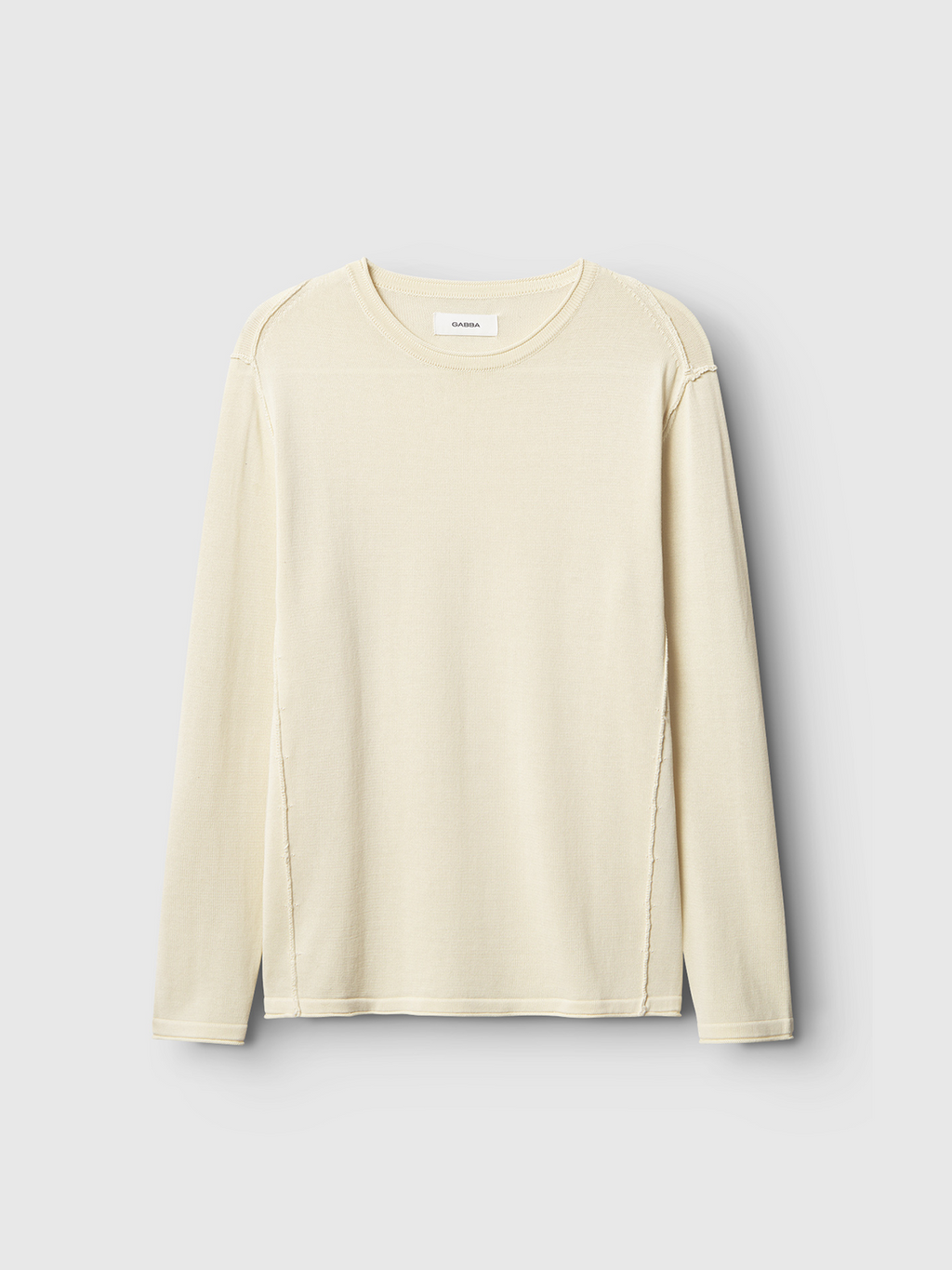 The Bela Fix LS - Ecru Light by Gabba is a beige, long-sleeve shirt crafted from premium knit 100% cotton. Featuring a round neckline and visible shoulder and side seams, it promises superior comfort. Displayed against a light gray backdrop.