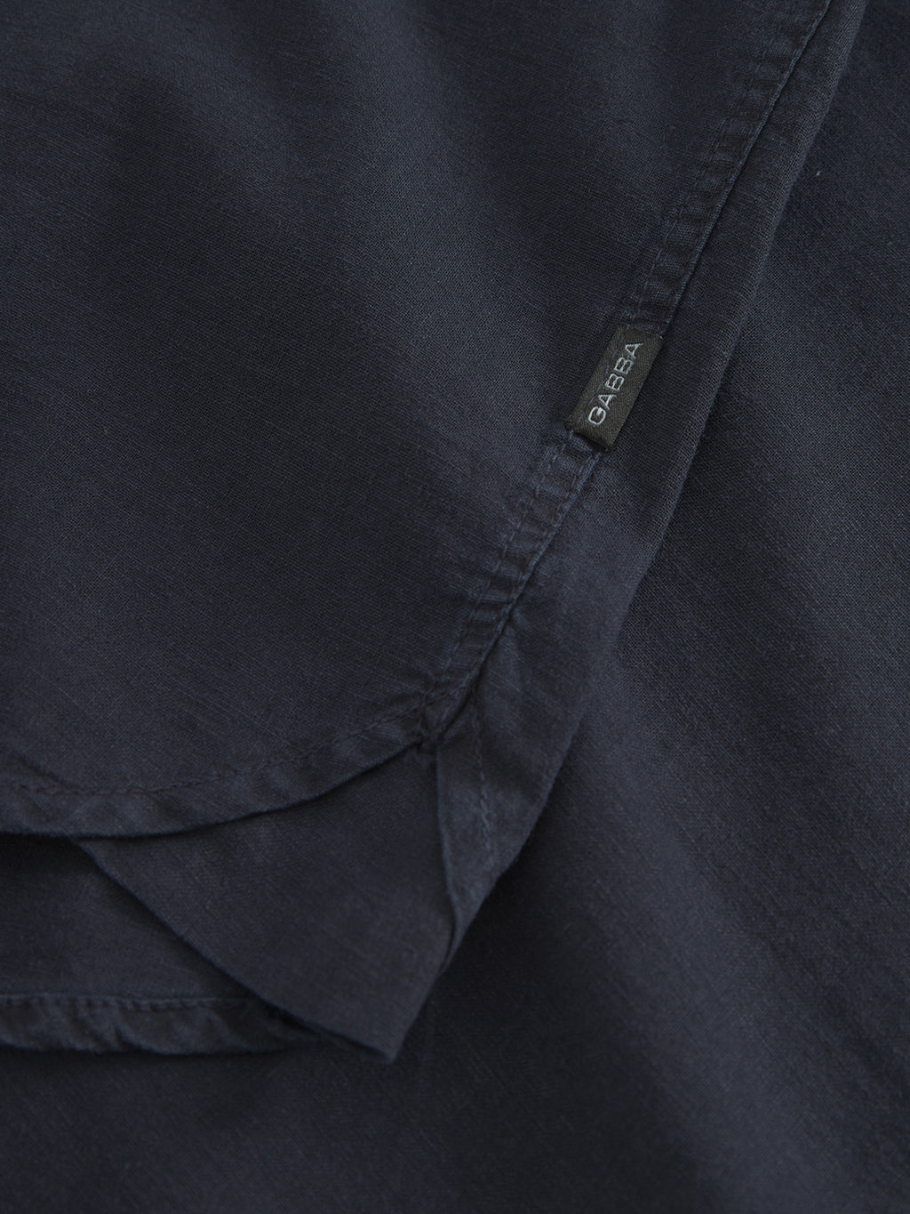 Close-up of a dark blue fabric with visible stitching and a small tag that reads Gabba, embodying the comfort of the Sven Reg Lino LS - Night Sky shirt.
