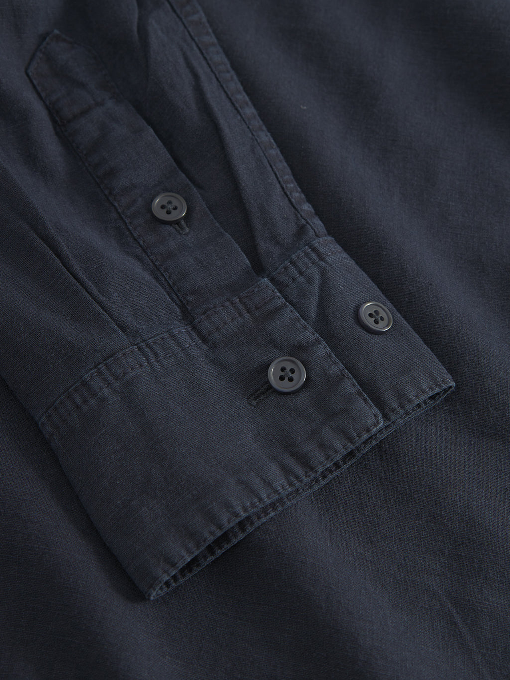 Close-up of the Sven Reg Lino LS - Night Sky shirts dark blue sleeve from Gabba, highlighting the neatly sewn buttoned cuff with two black buttons. The premium fabric delivers a smooth texture for comfort and style, with precise, evenly spaced stitching.