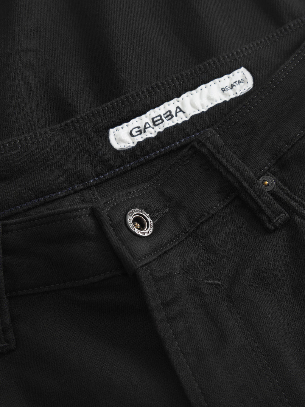 Close-up of the waistband and button of the Max Sword - Black Denim jeans by Gabba, featuring a white fabric label with the brand name and a small RE-TAKE tag.