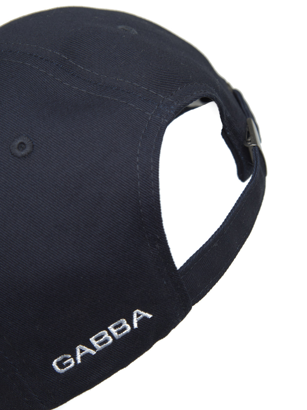 Close-up of the Cashier Cap - Night Sky by Gabba, a navy blue baseball cap made from 100% cotton twill. It features GABBA embroidered in white on the side and has an adjustable strap for a perfect fit.