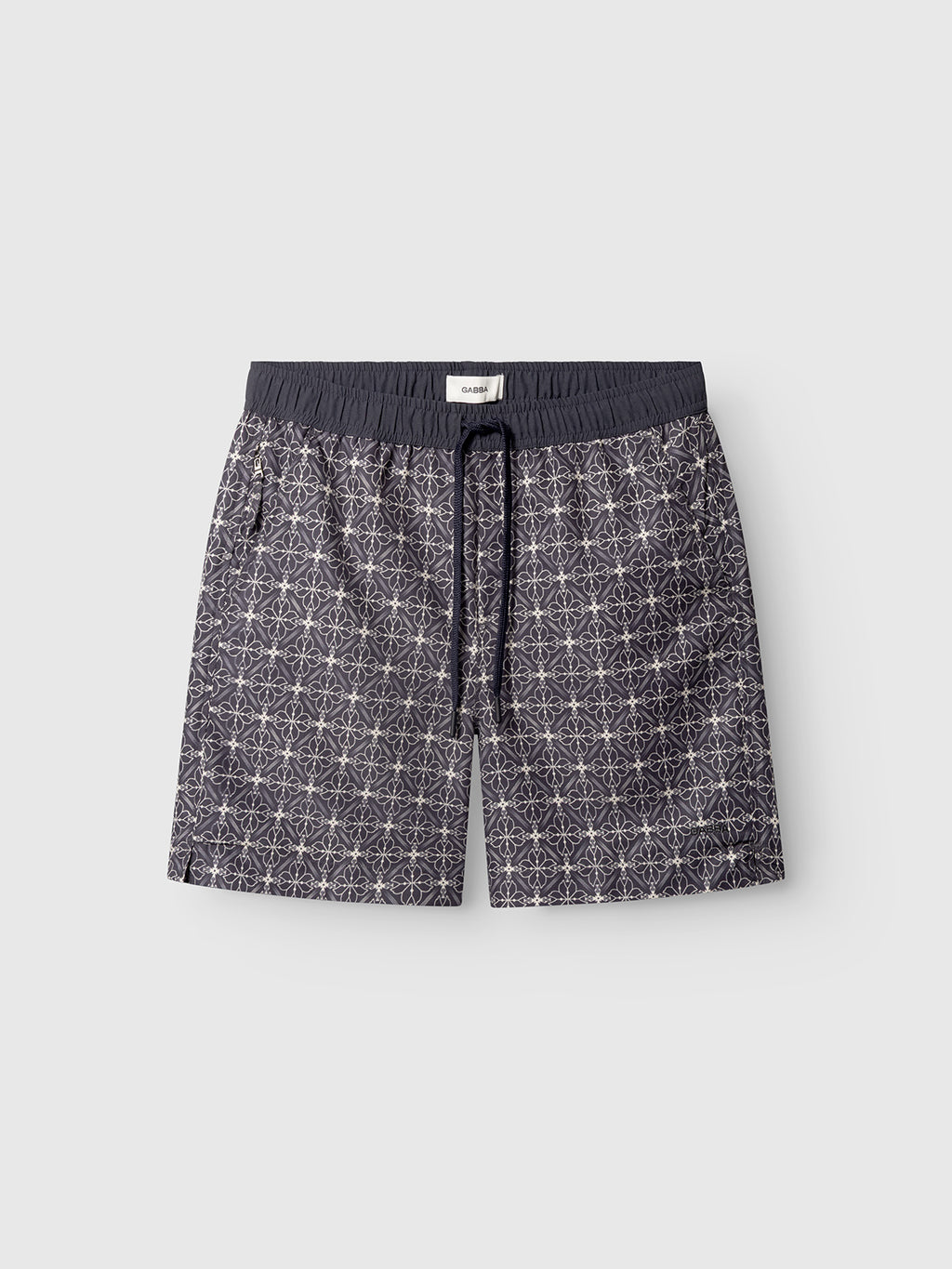 Gabba’s Jackson Print - Multi Pattern mens swim shorts feature an elastic waistband, white geometric star design on a dark base, side pockets, and are shown on a light gray background.