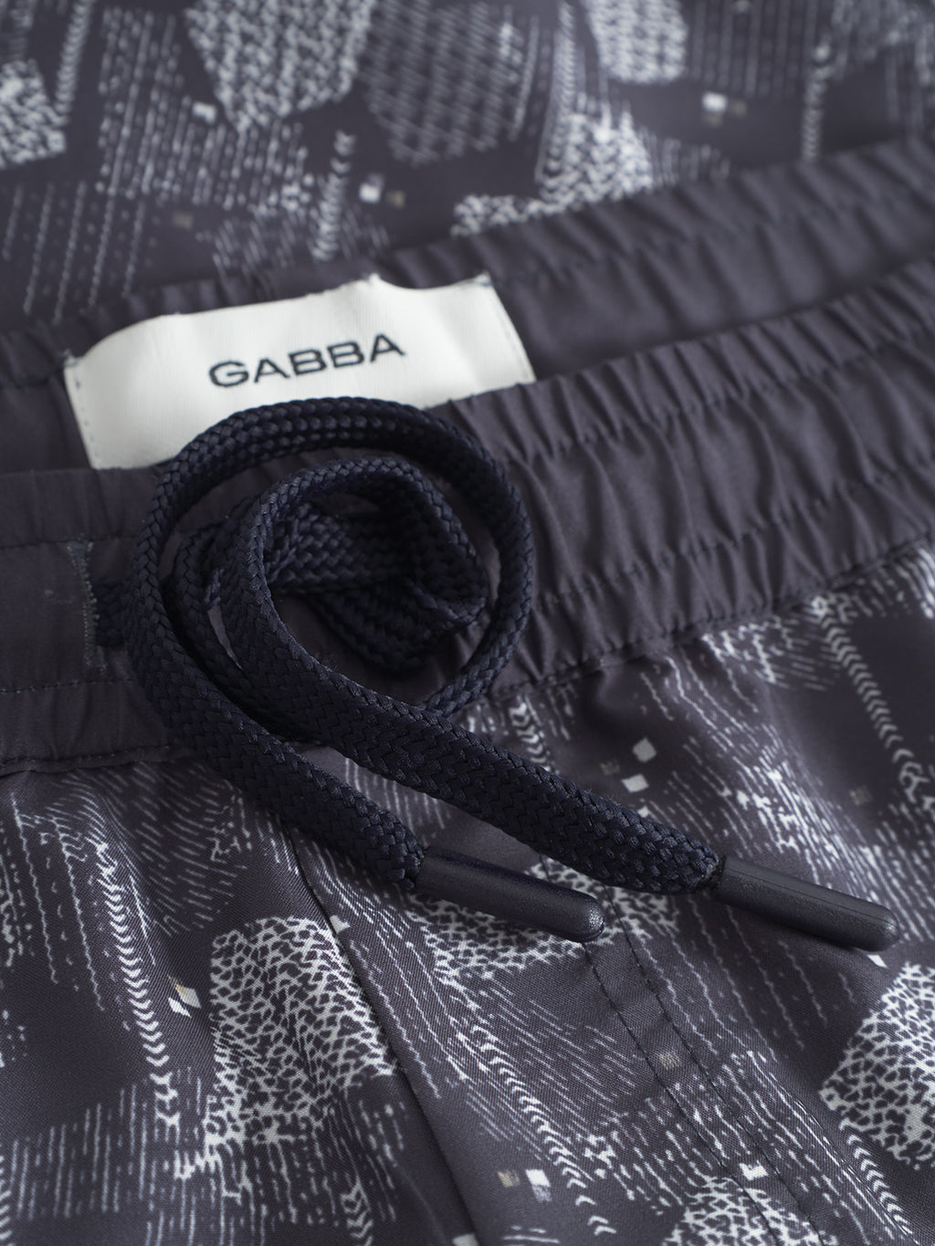 Close-up of Jackson Print - Blue Pattern pants by Gabba, featuring a blue pattern, elastic waistband, dark drawstring, and a white Gabba label.