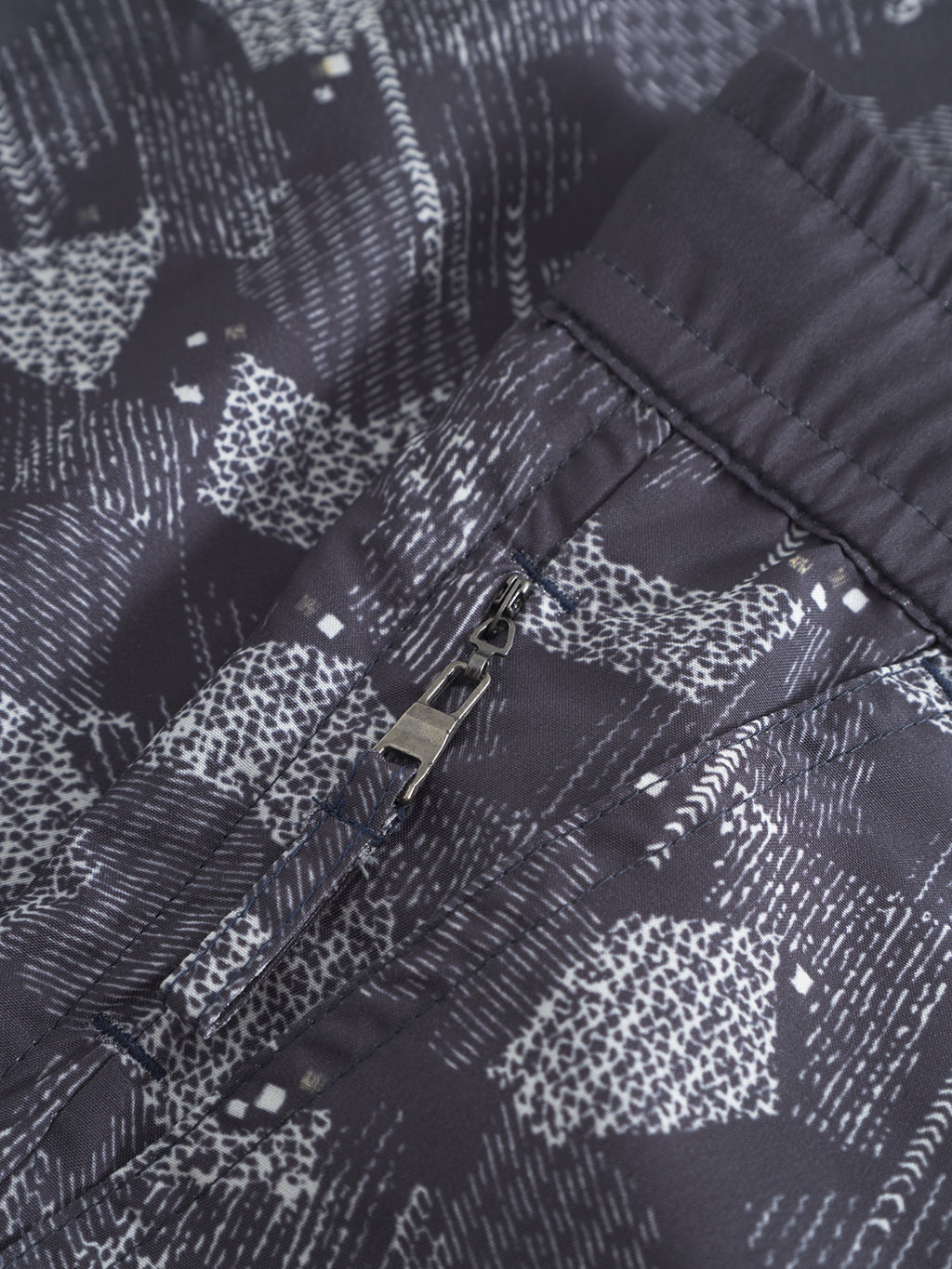 The Jackson Print - Blue Pattern swim shorts from Gabba feature a secure closure and elastic waistband, combining style and convenience—much like the adaptable zipper on a classic jacket.