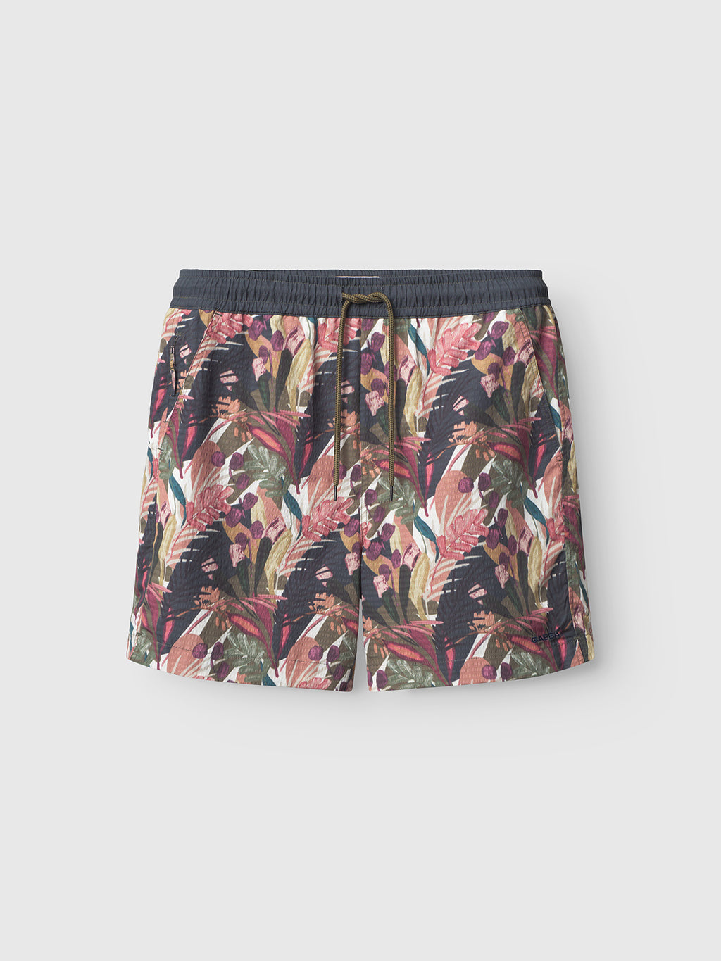 The Gabba Jackson Seer Print - Flower Mix swim shorts feature a relaxed fit, drawstring and elastic waistband, side pockets, and a vibrant tropical leaf design in green, red, purple, and beige on a light background.