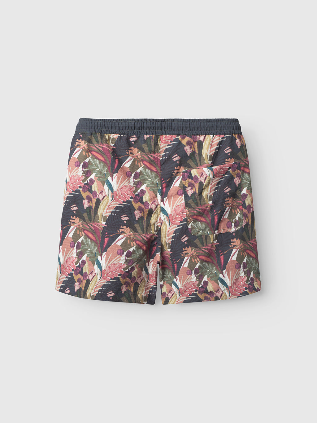 Back view of Gabbas Jackson Seer Print - Flower Mix swim shorts, featuring an elastic waistband, side pockets, and a vibrant tropical floral design in red, pink, green, and beige on a dark background.