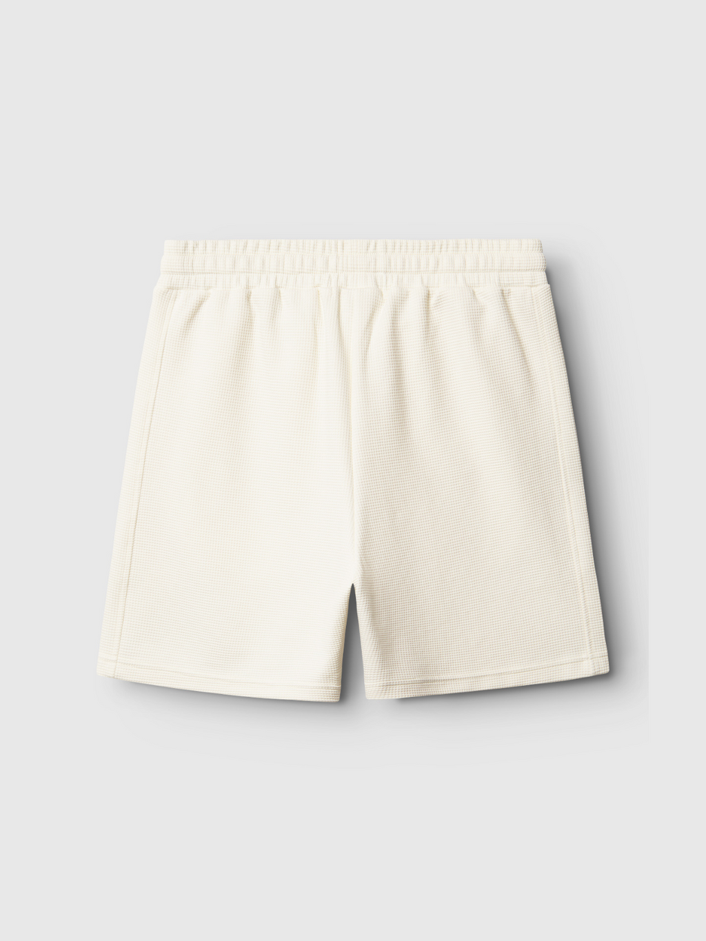 The Gabba Tim Waff - Bone White shorts feature a minimal off-white ribbed knit design with an elastic waistband, waffle fabric for comfort, and no visible logos or pockets. Shown laid flat on a light gray background.